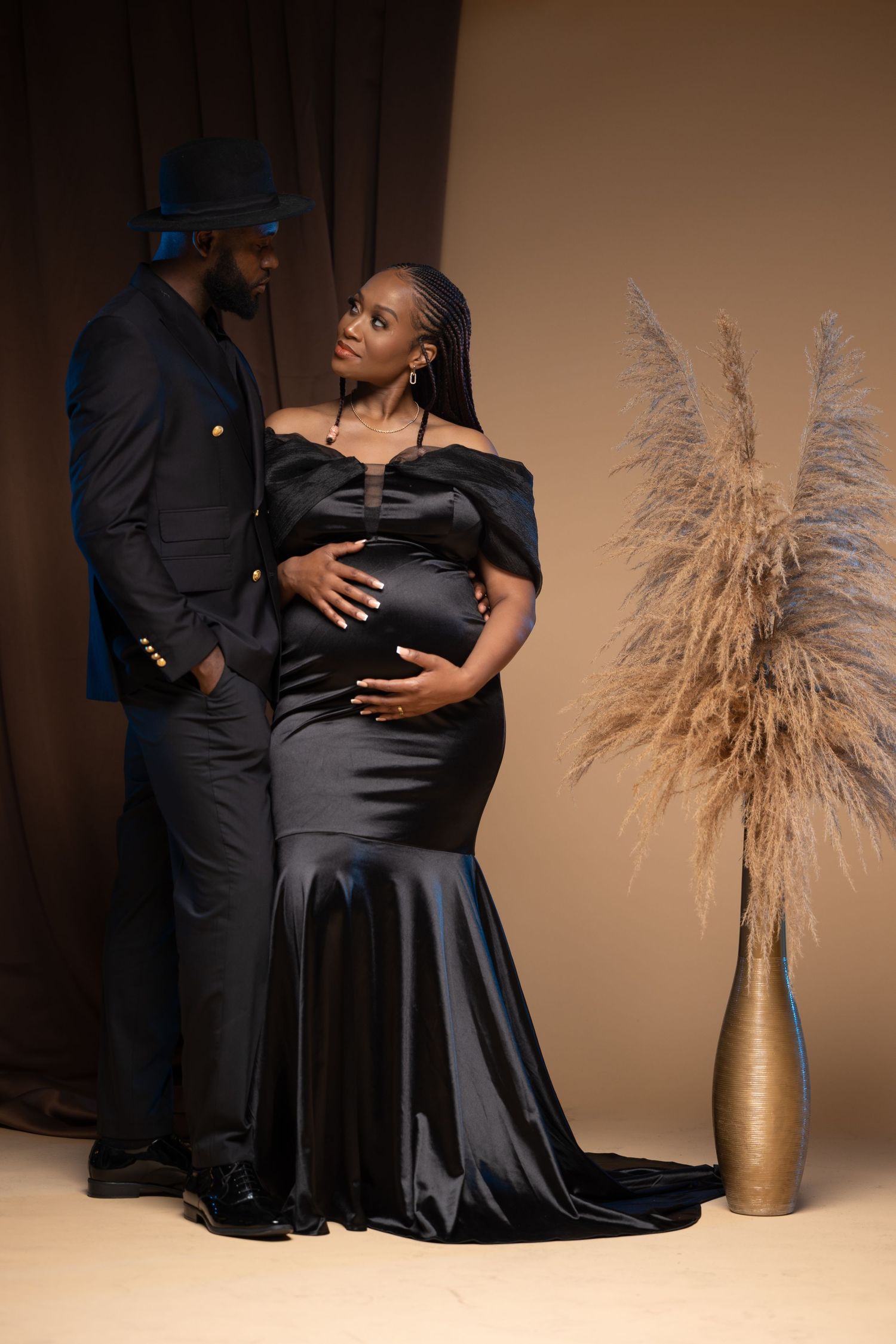 Elegant maternity portraits in black formal wear with decorative pampas grass decor.