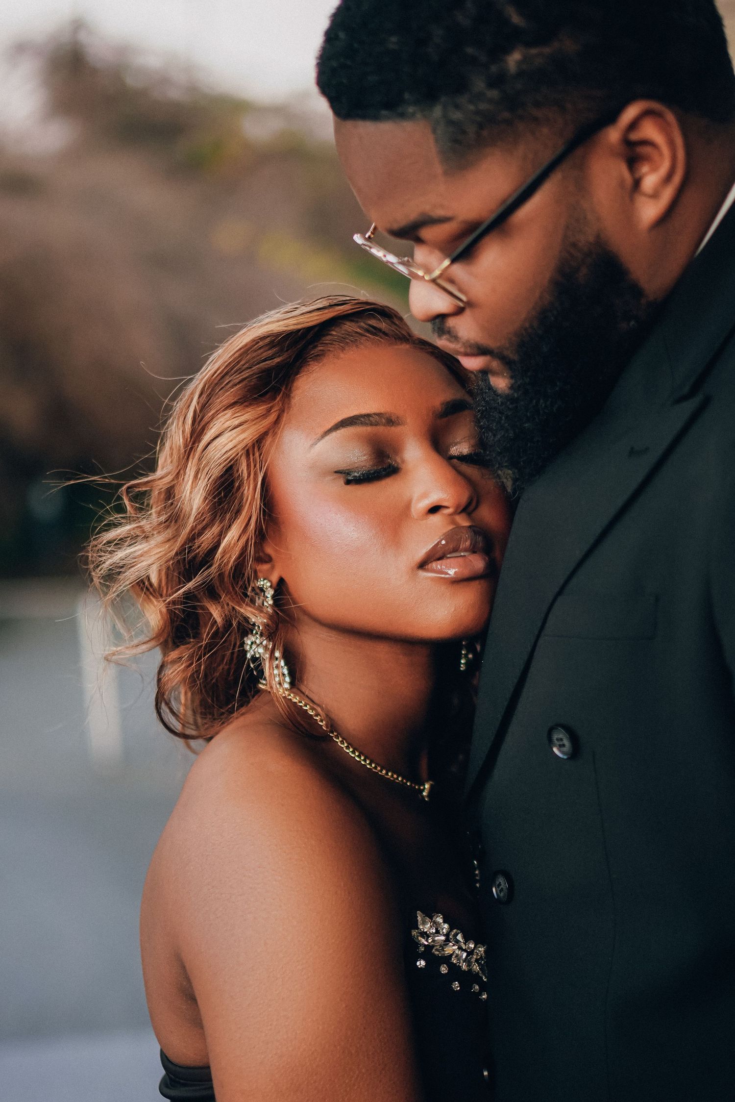 Romantic close-up portrait of couple in formal attire during sunset photoshoot.