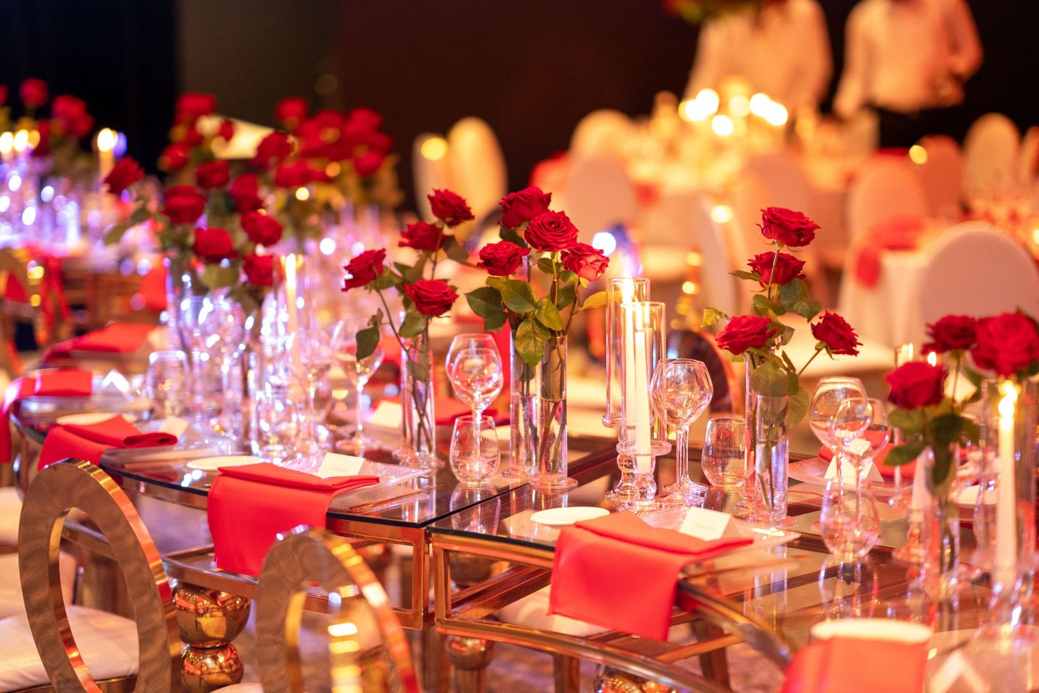 Elegant wedding reception table setting with red roses and crystal glassware.
