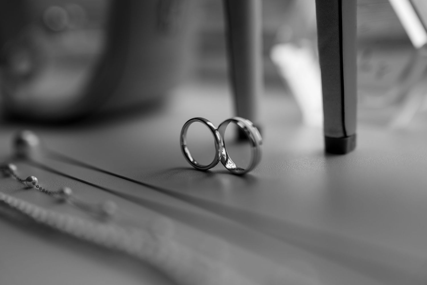 Close-up of wedding rings on reflective surface in black and white.