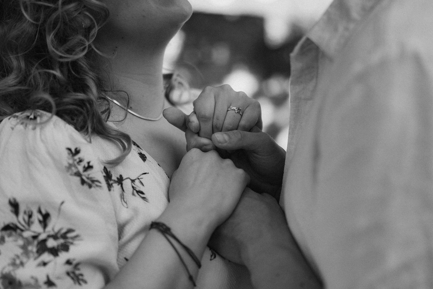 Black and white close-up of hands tenderly clasped together in an intimate moment.