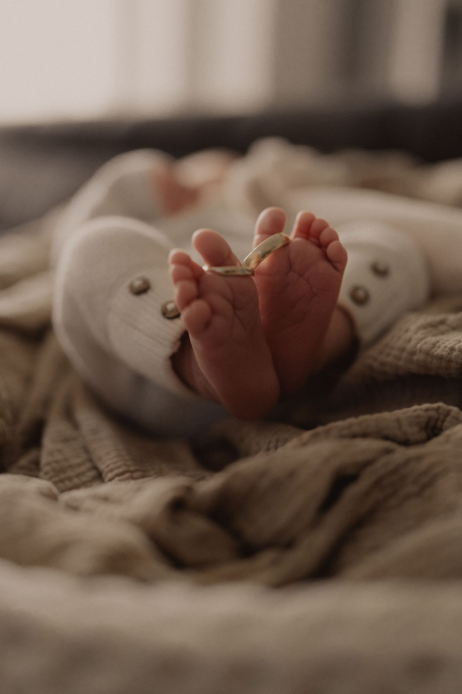 Newborn baby's delicate feet resting on cozy neutral bedding.