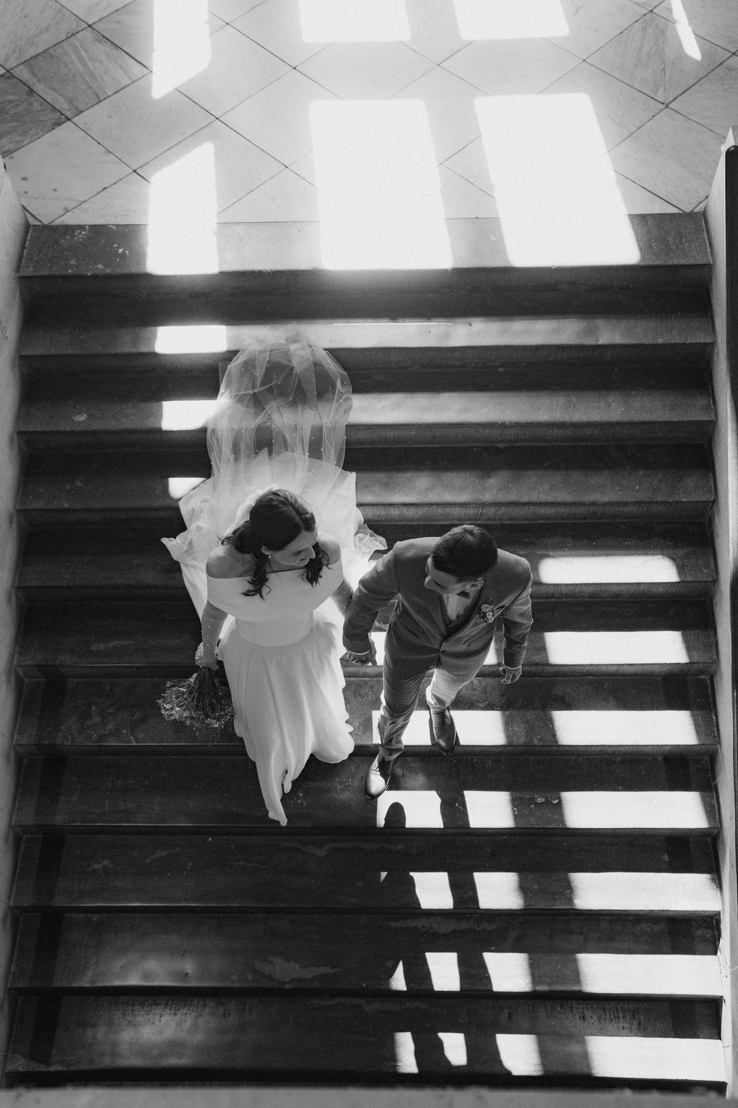 Wedding couple descending stairs in black and white photography.