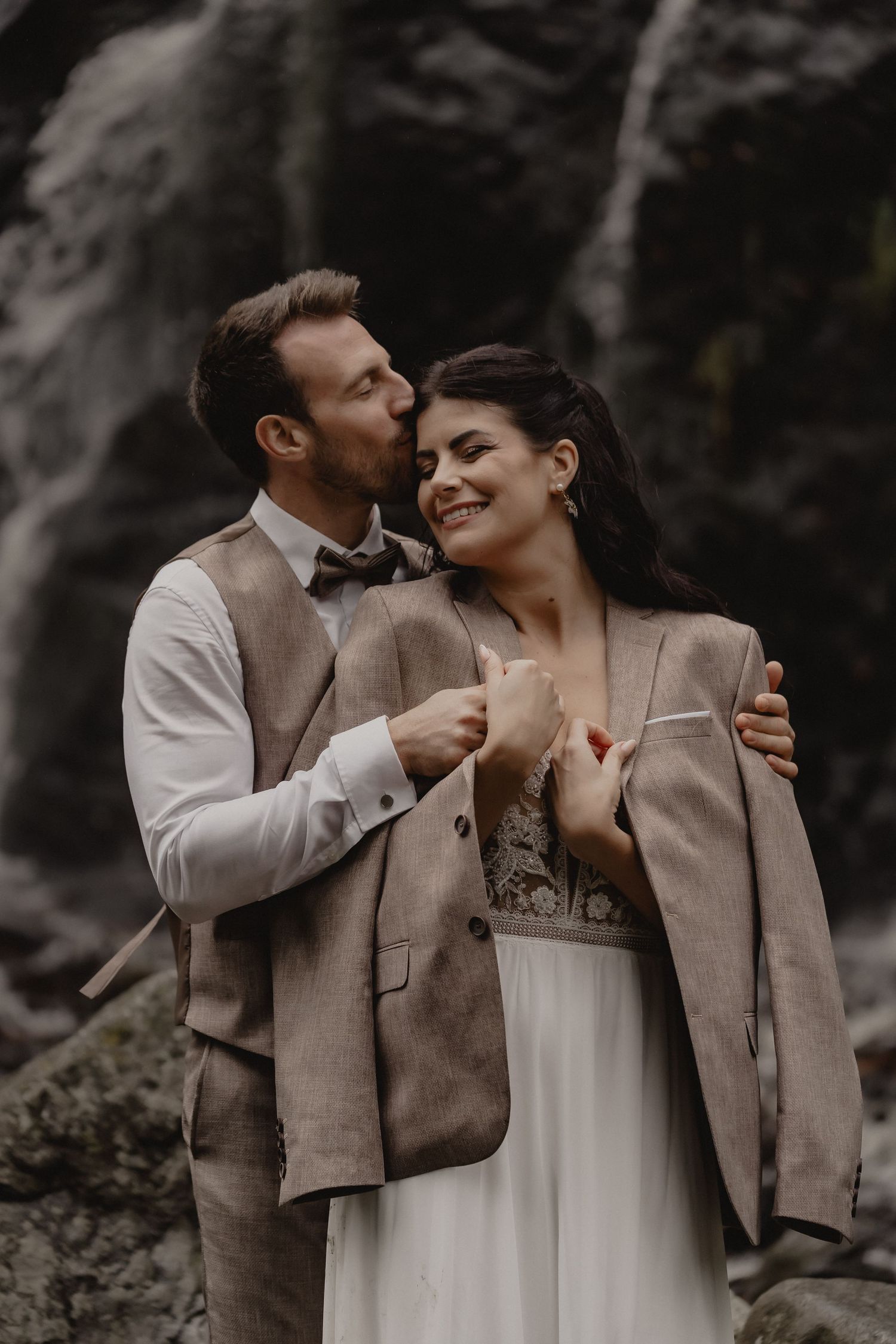A romantic wedding photoshoot showing tender moments between a couple in beige and white attire against a rocky backdrop.