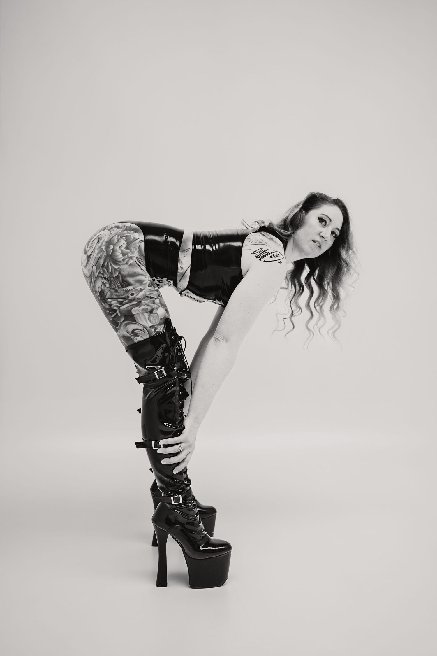 A figure in black lace and platform boots poses dynamically in a sequence of artistic black and white photographs.