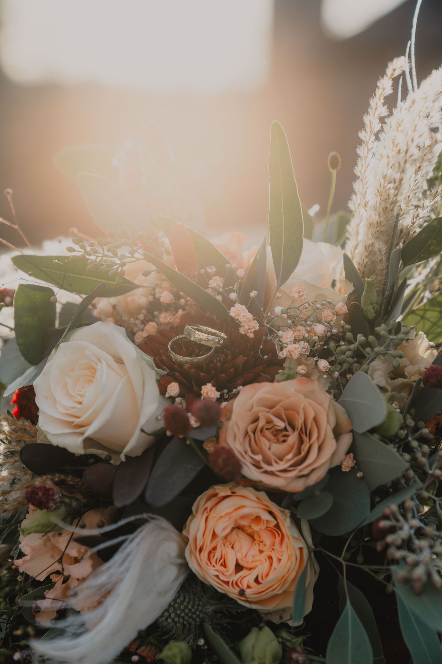 Romantic floral arrangement with peach roses and eucalyptus leaves in soft natural lighting.