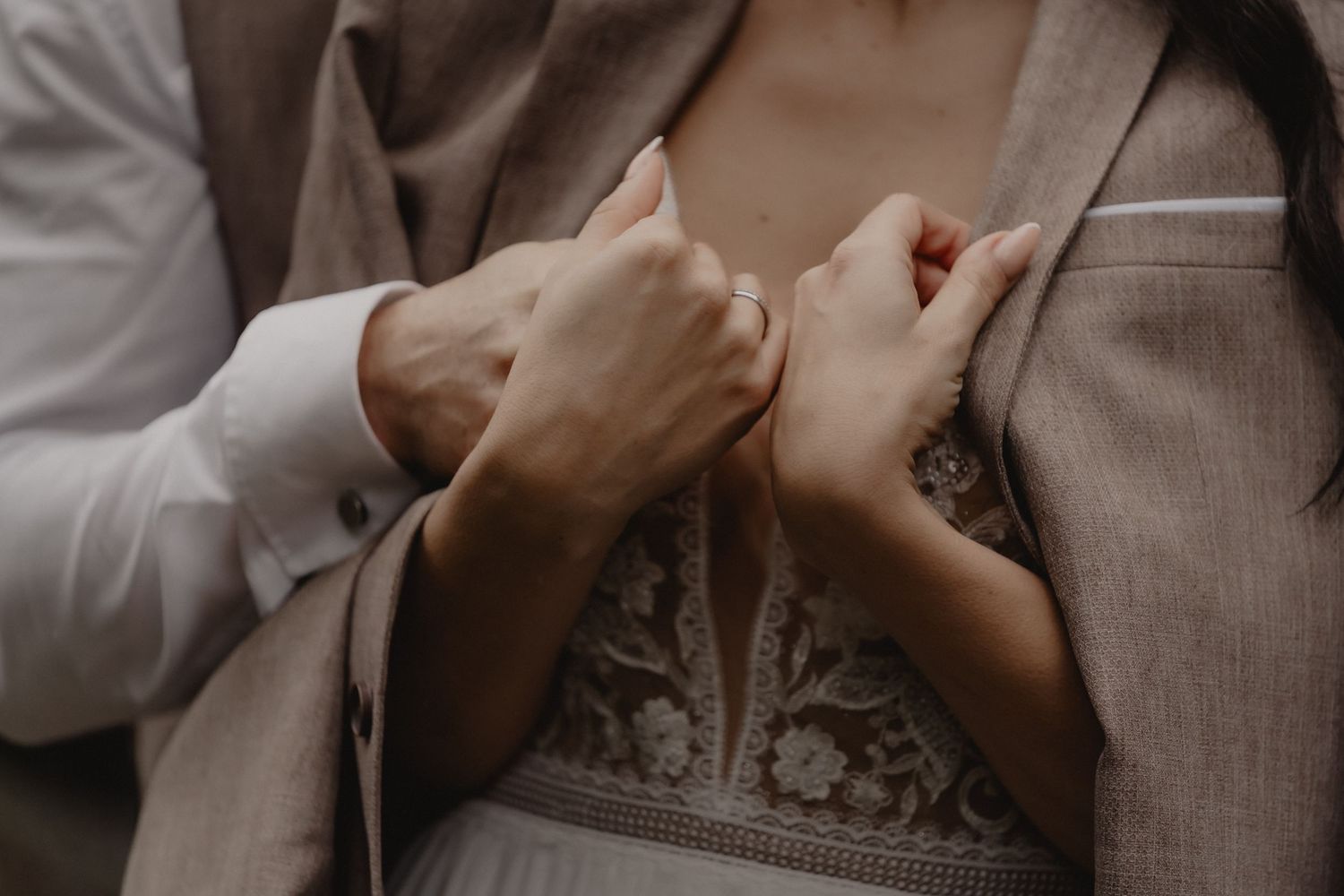 Intimate close-up of hands and formal attire details in muted tones.