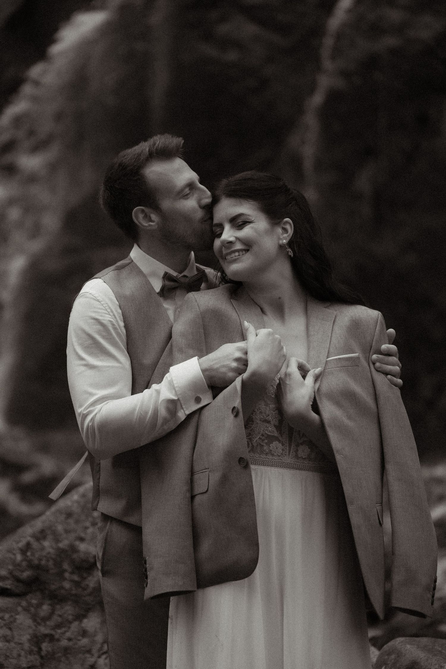 Black and white photo series of a couple sharing intimate moments against a moody backdrop.