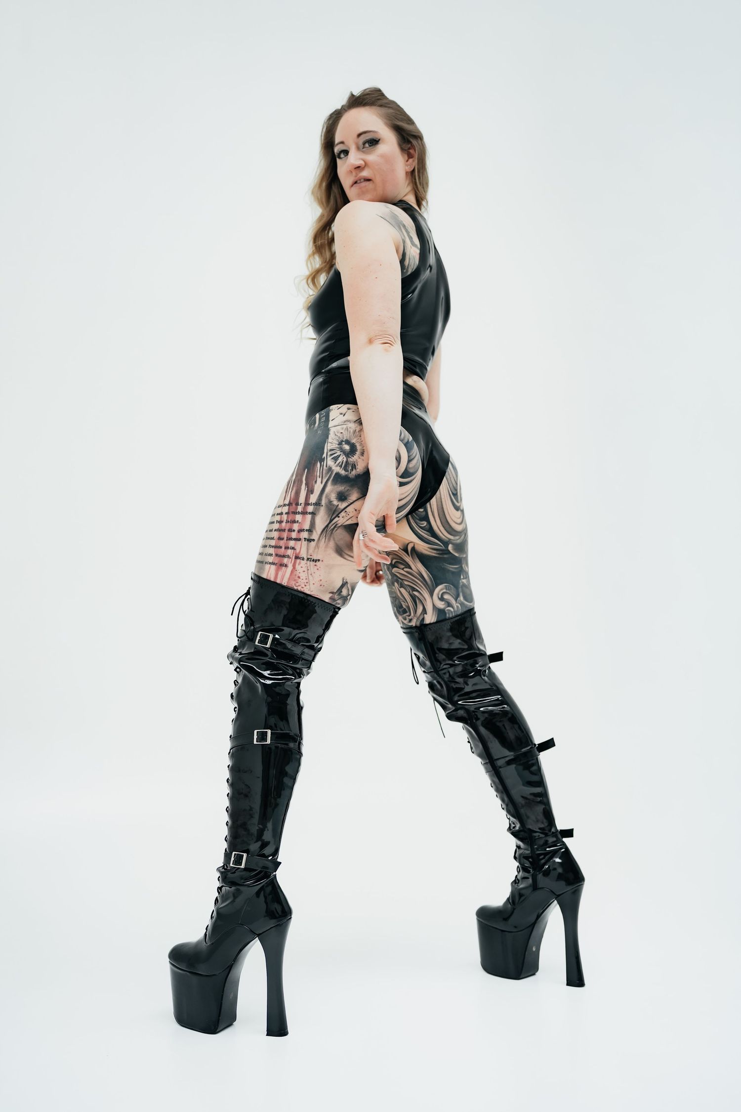Model wearing black leather platform boots with buckles and straps in different poses against white background.