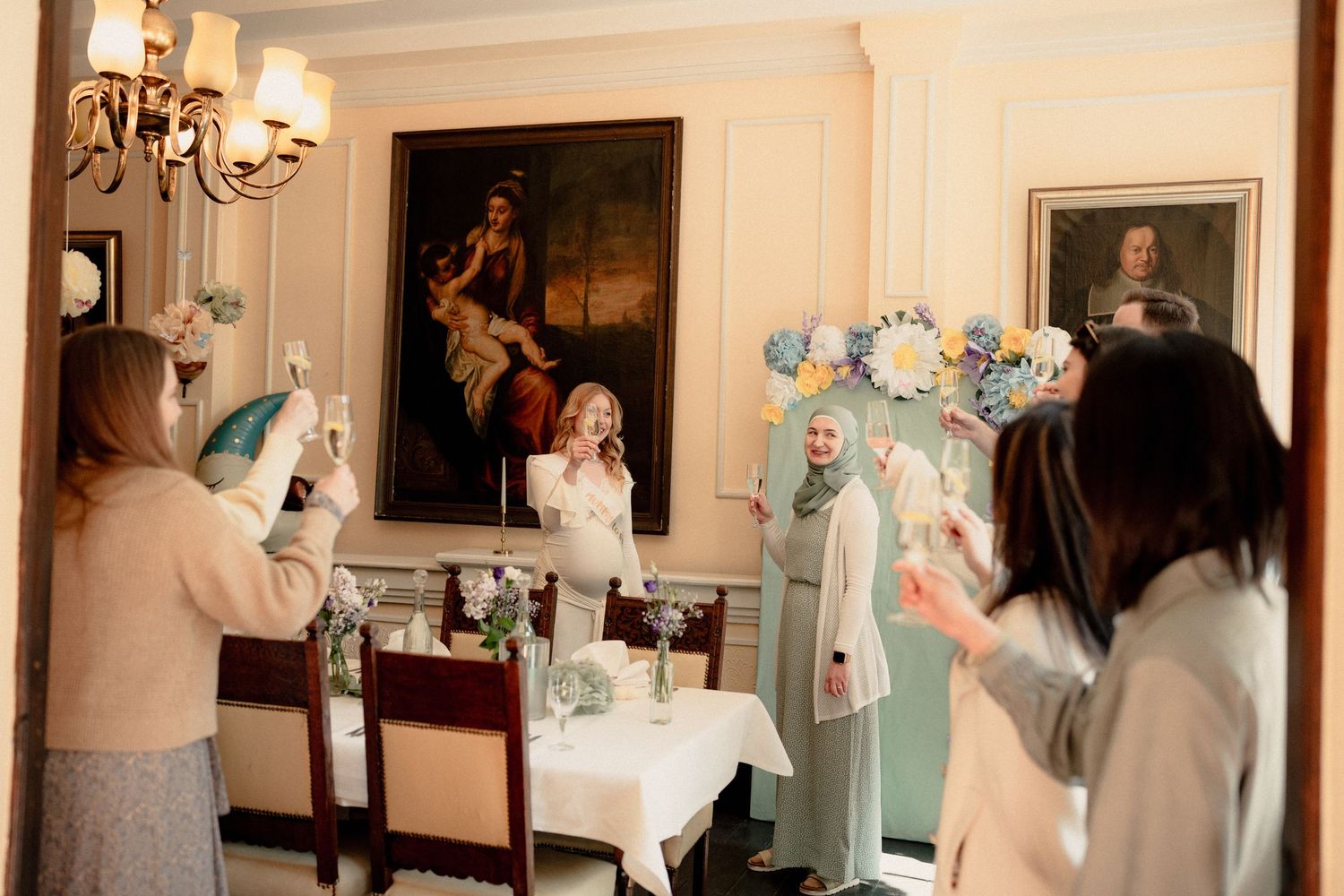 Women celebrating at a baby shower with floral decorations in an elegant dining room.