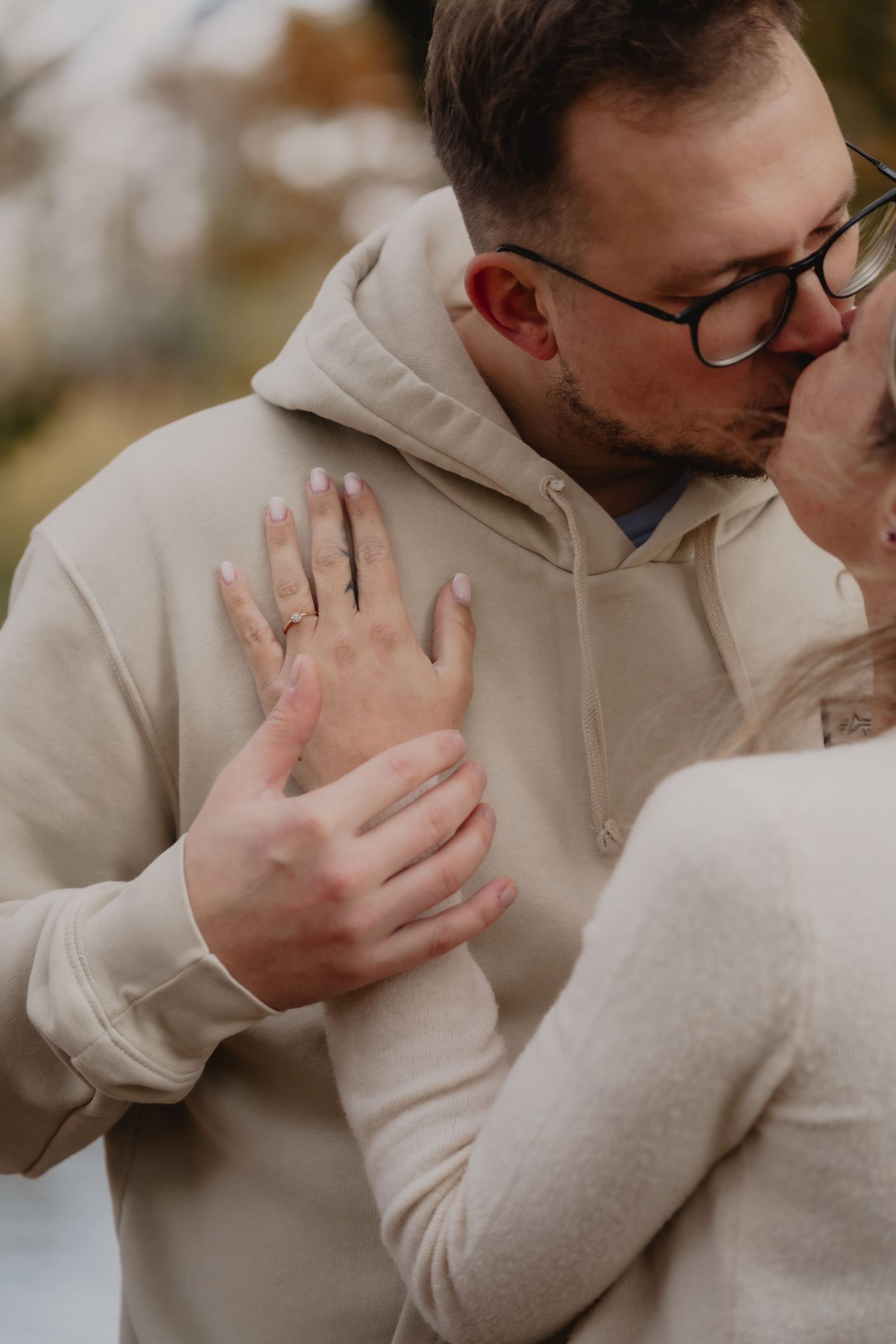 An intimate moment captured between two people wearing cream-colored sweaters outdoors.