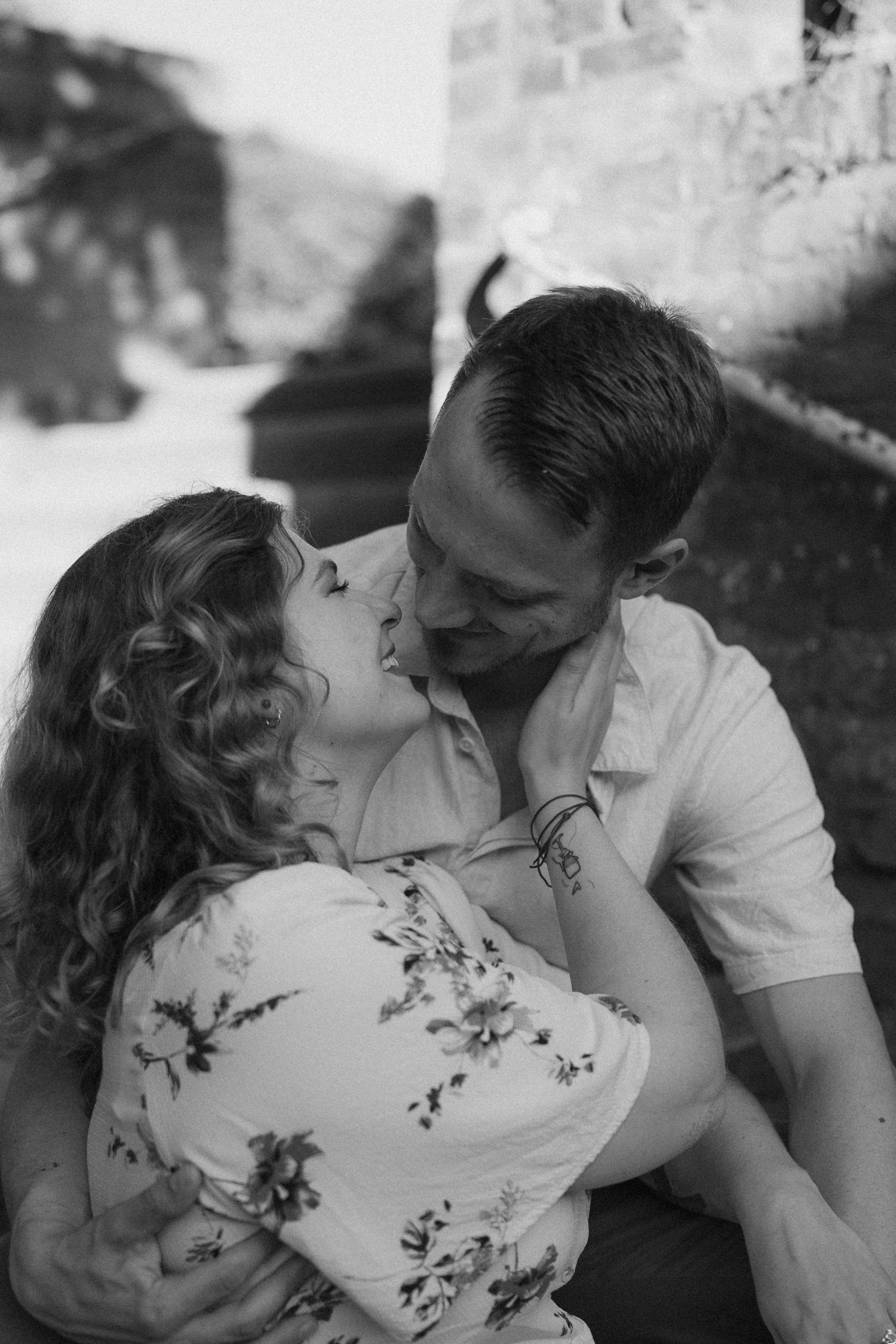 A black and white intimate portrait of a couple sharing a romantic moment on stone steps.