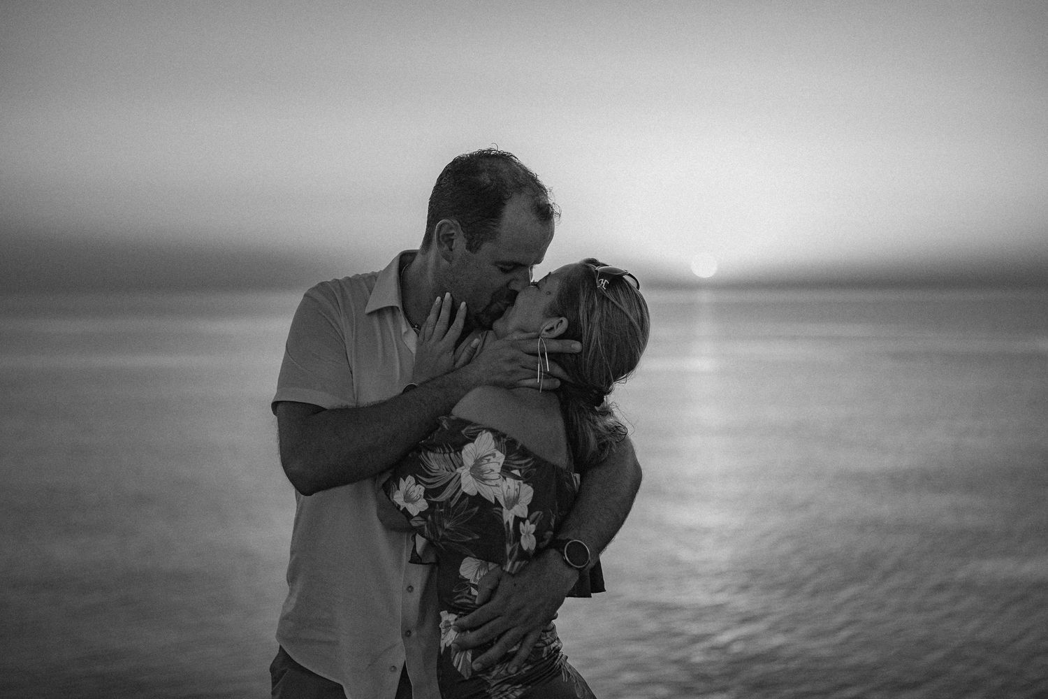 Couple sharing romantic moment against ocean view in black and white.
