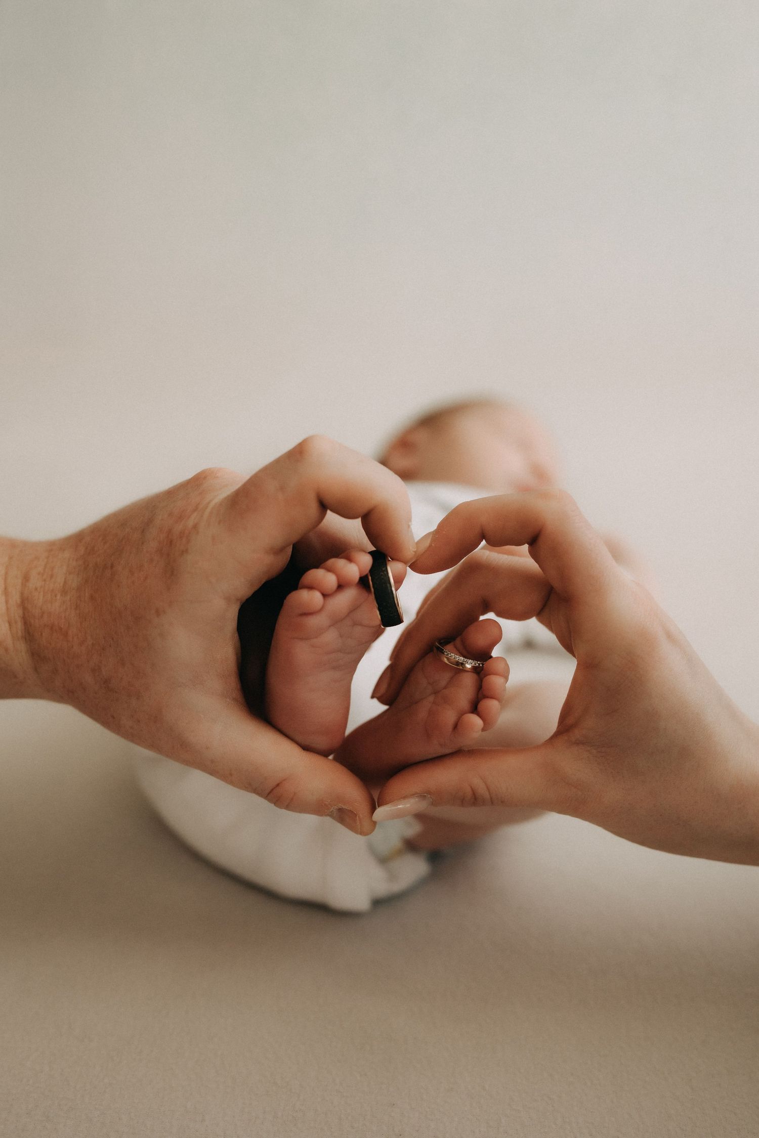 Two hands forming a heart shape together against a light neutral background in a minimalist style.