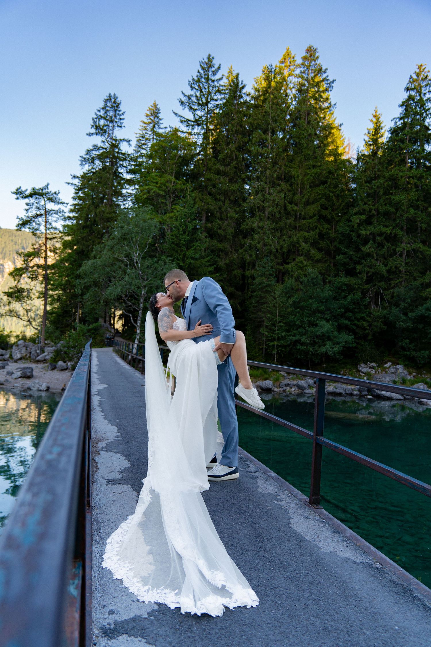 Wedding couple poses along a mountain pathway with dramatic forest and mountain vistas.