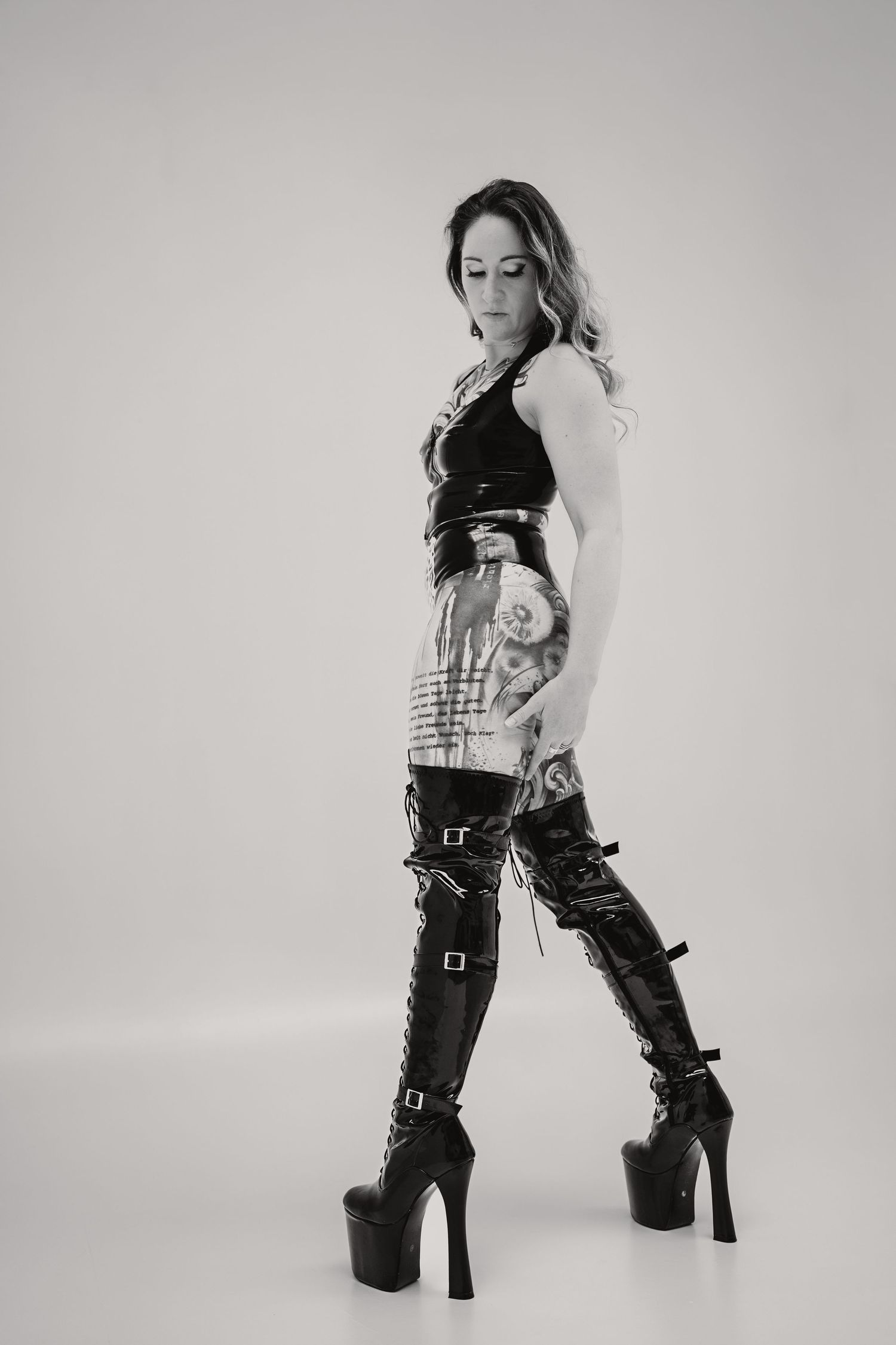 Black and white fashion photo showing edgy punk rock style with platform boots, buckled leg straps and tattoo details.