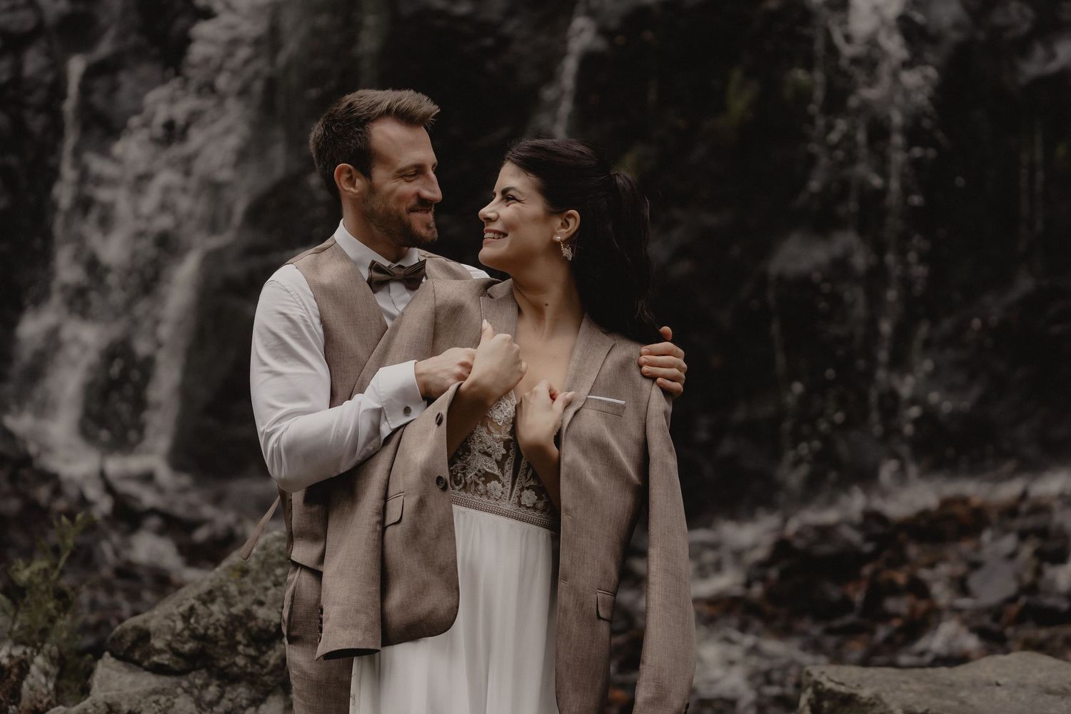 Intimate wedding moments captured against a moody forest waterfall backdrop.