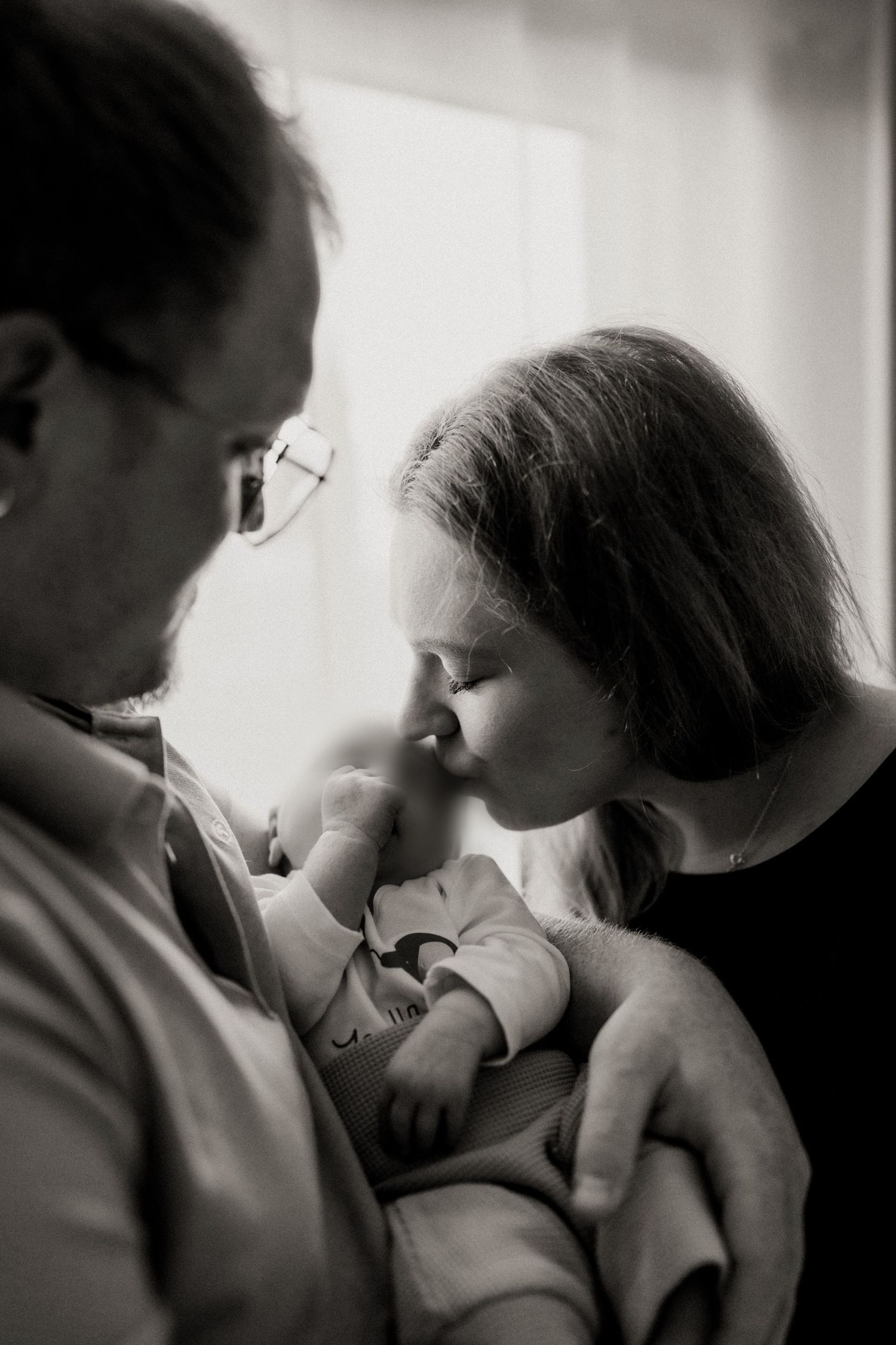 A tender black and white photo sequence showing a parent lovingly cradling and bonding with their newborn baby.