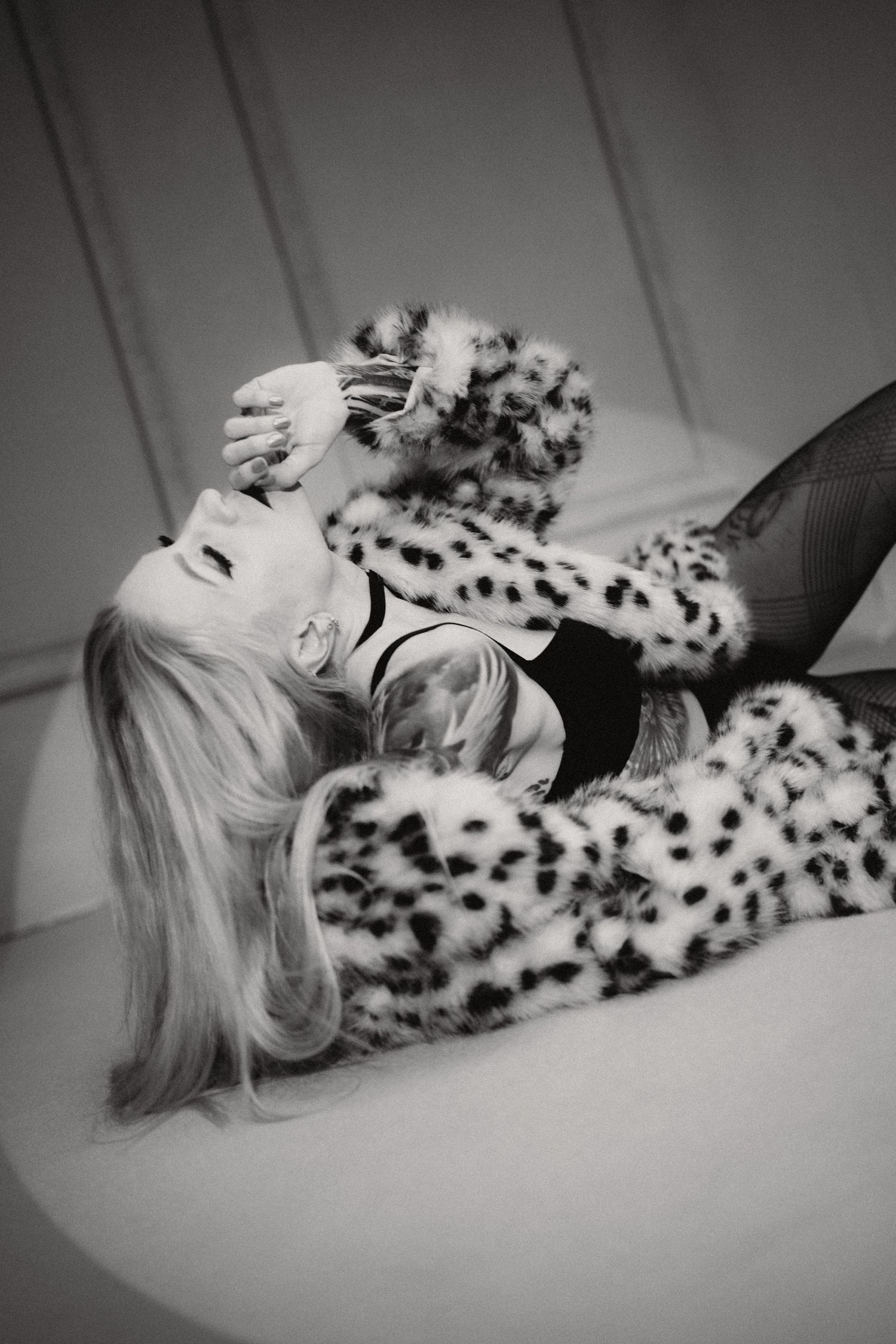Black and white photo showing someone lying back in cozy leopard print slippers and matching loungewear.
