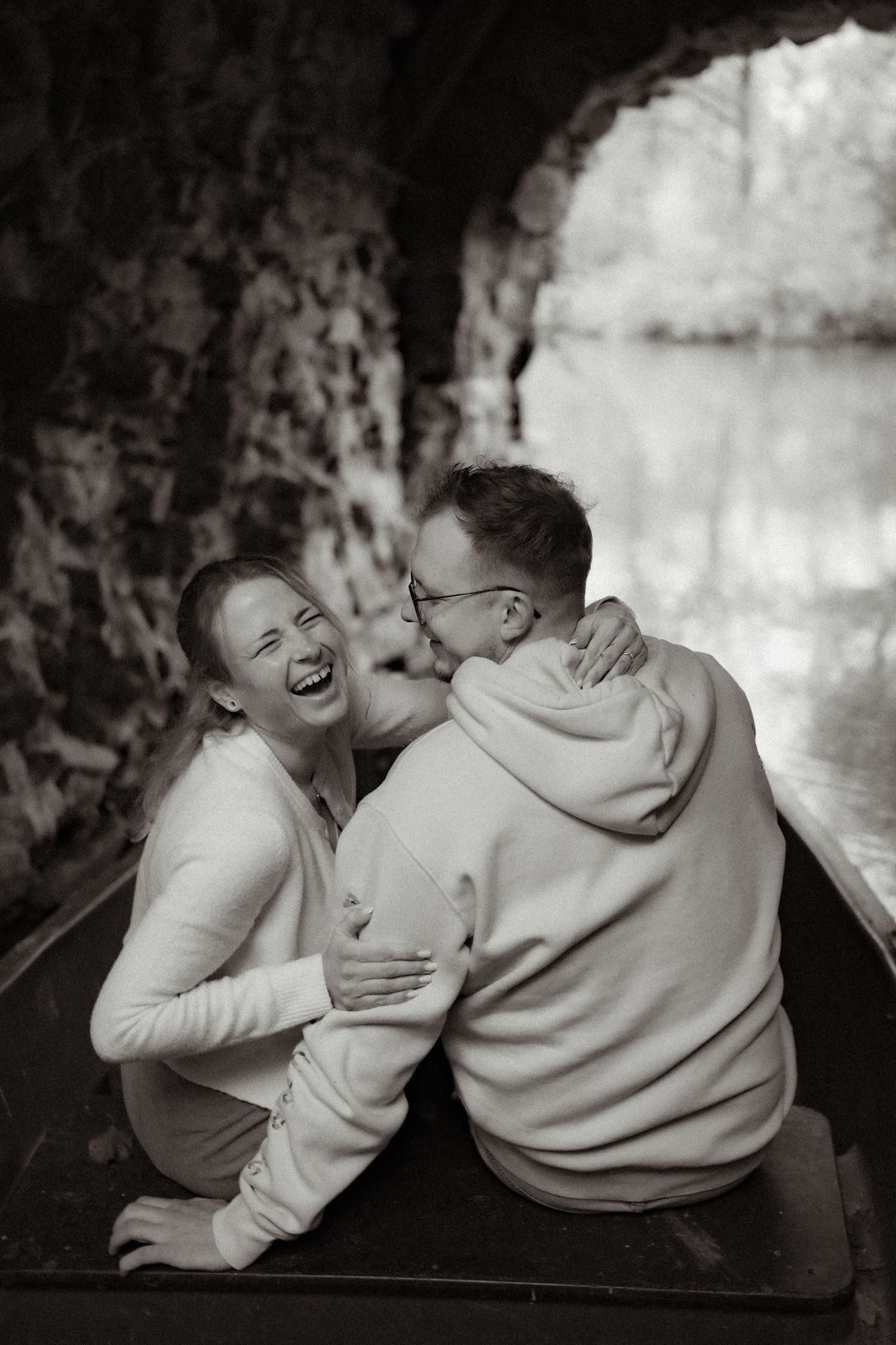Two people laughing together while sitting on a bench in black and white photography.