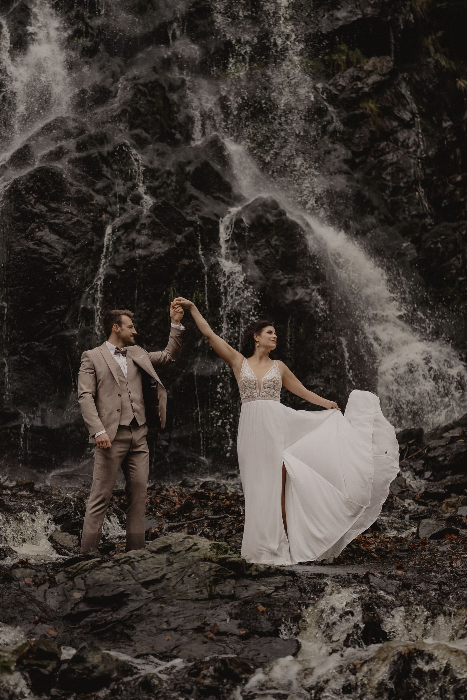 Artistic wedding photos captured against a dramatic waterfall backdrop in a forest setting.