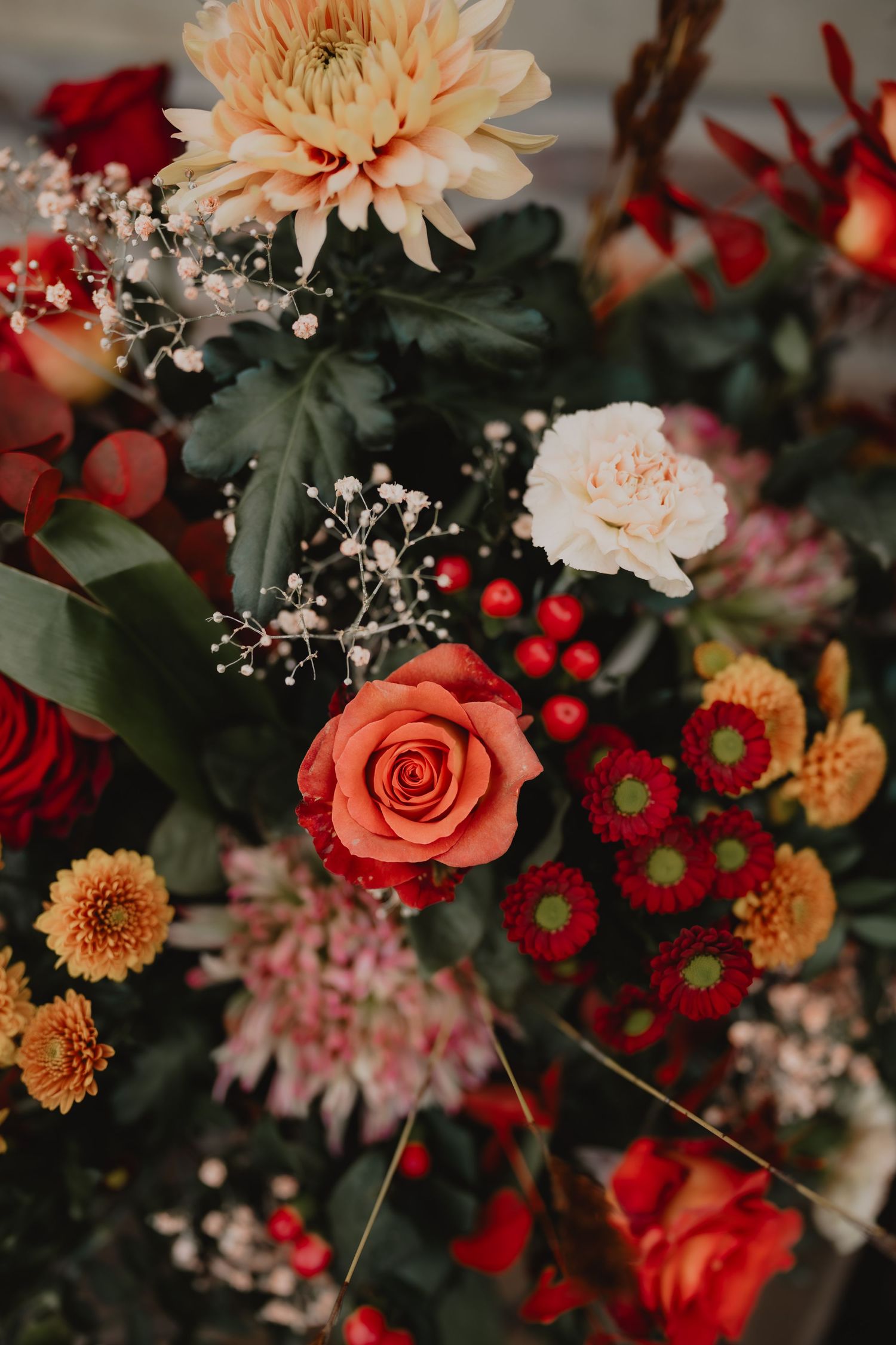 Romantic floral arrangement with peach dahlias, coral roses, and red blooms mixed with delicate baby's breath.