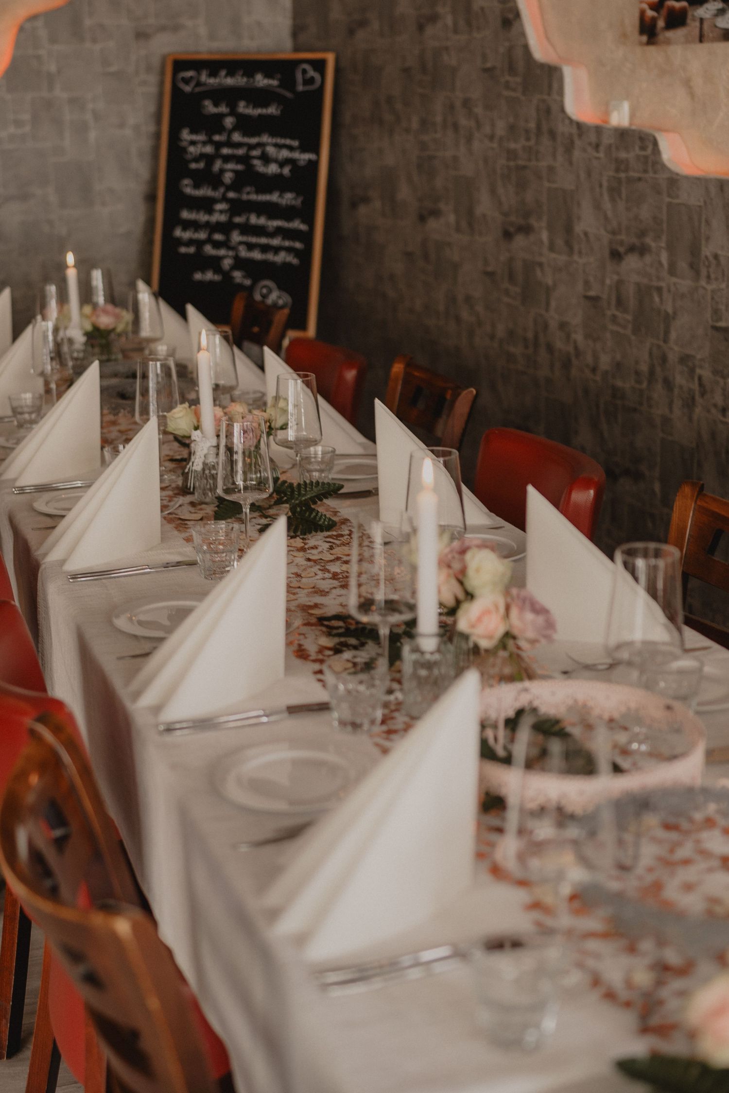 Elegant wedding reception table set with white linens, candles and delicate floral arrangements.