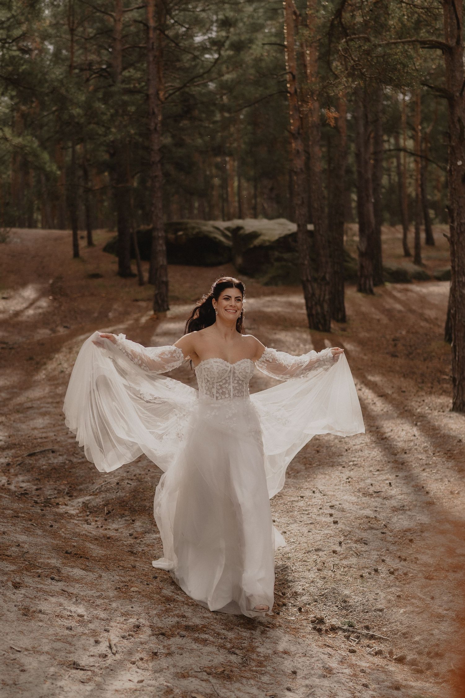 Ethereal bridal portrait on a forest path with flowing white gown movement.