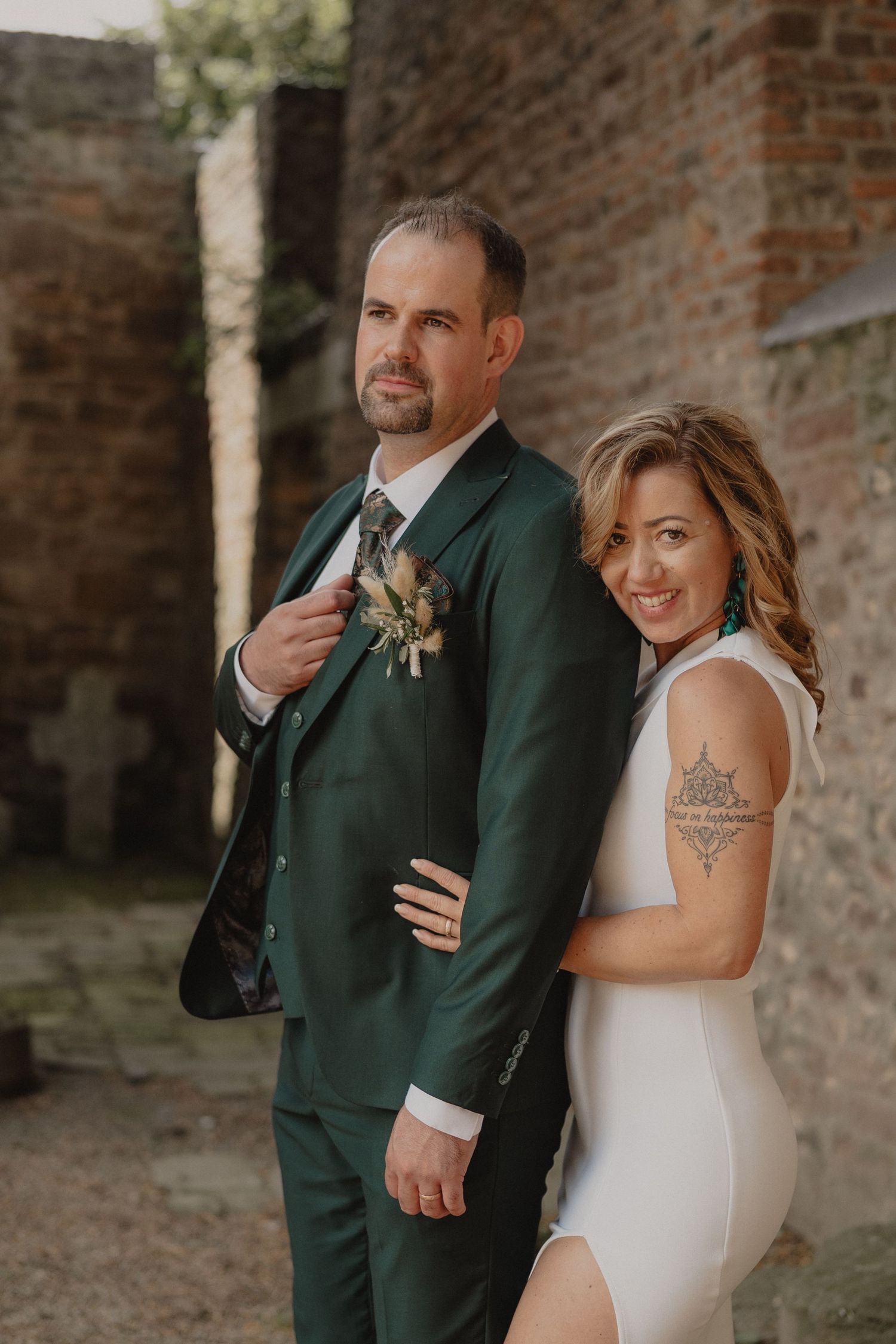 A playful wedding portrait featuring a couple in elegant attire posing against historic brick architecture.