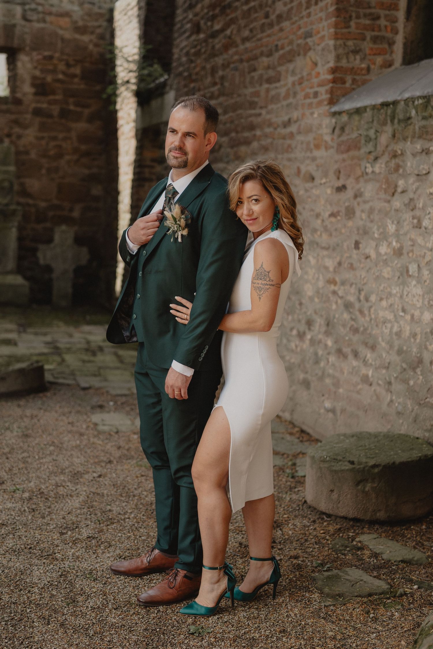 Candid wedding photos showcase couple's playful interaction against rustic brick backdrop.