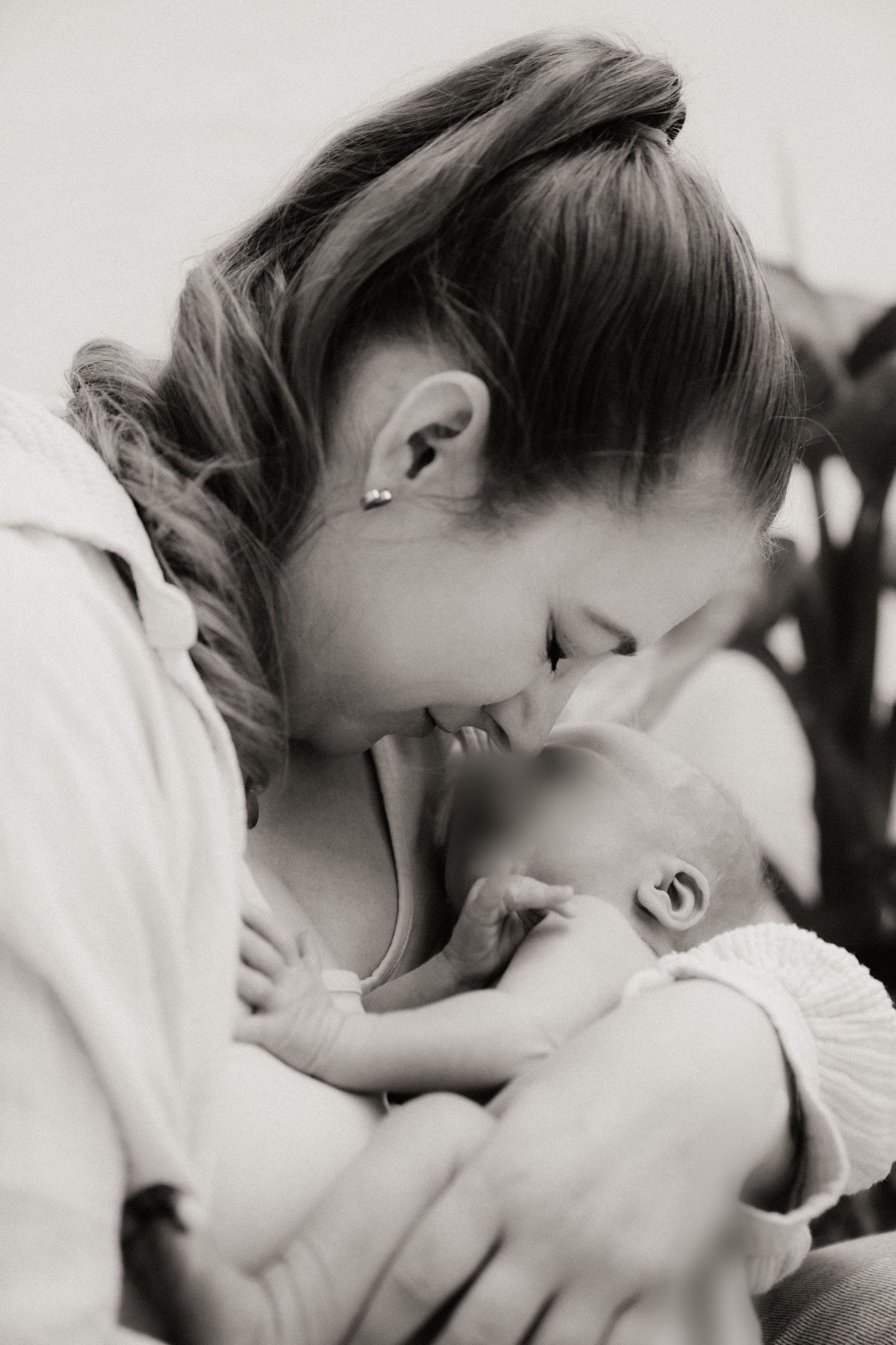 Black and white photo of a young mother tenderly holding and gazing at her newborn baby.