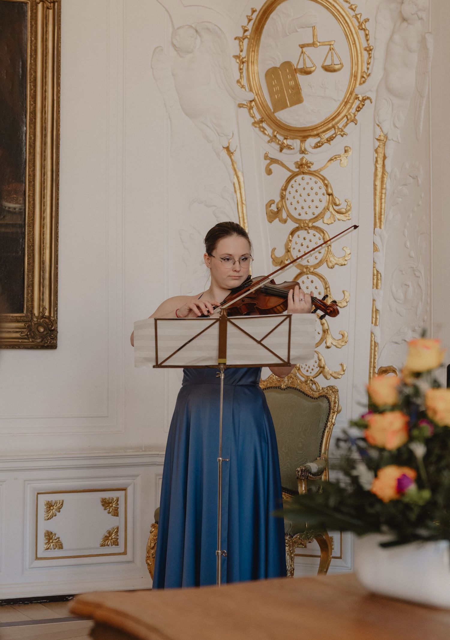 Elegant ballroom with ornate gold decor and musician performing.
