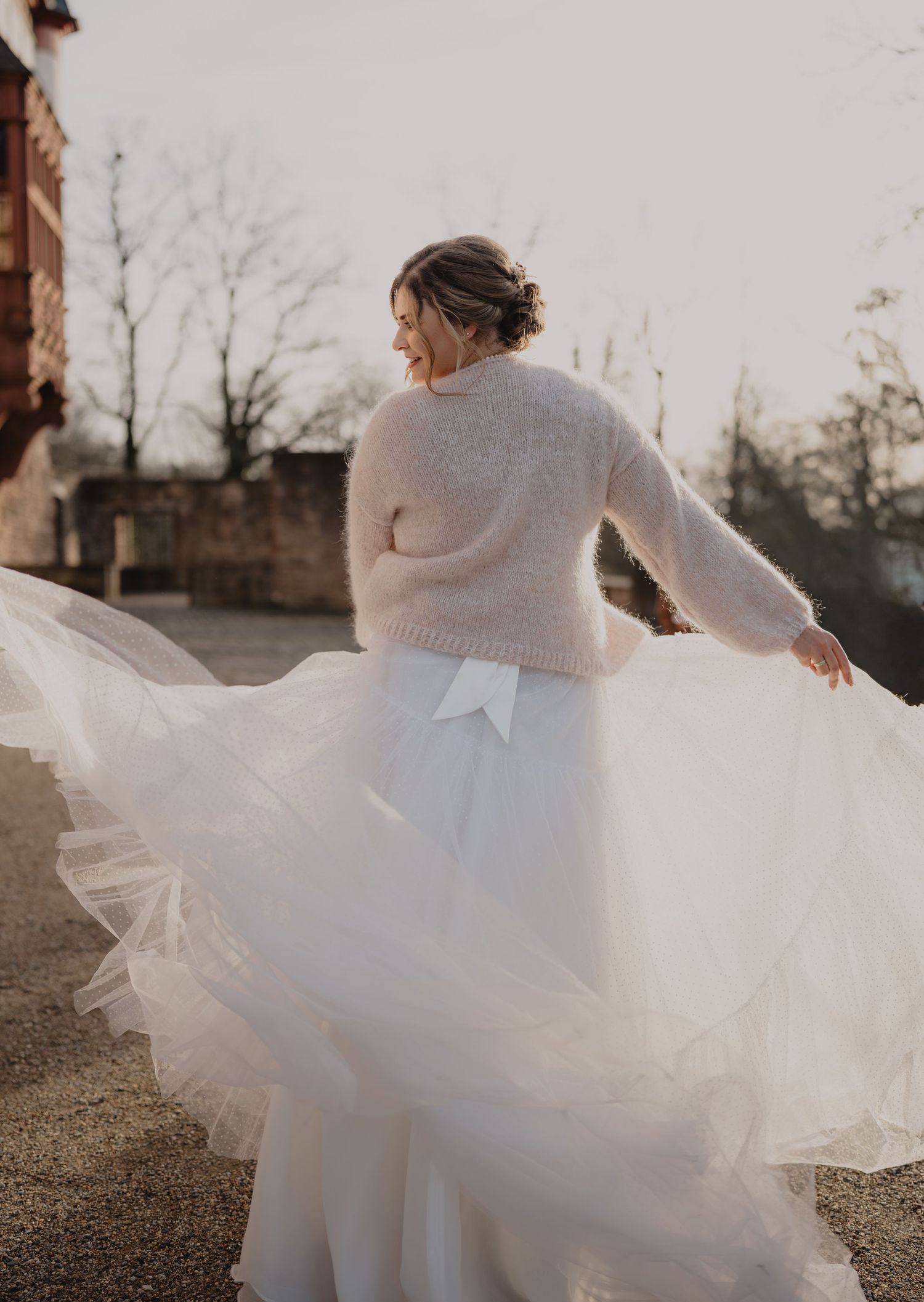 A bride in a flowing white dress twirls on a winter day.