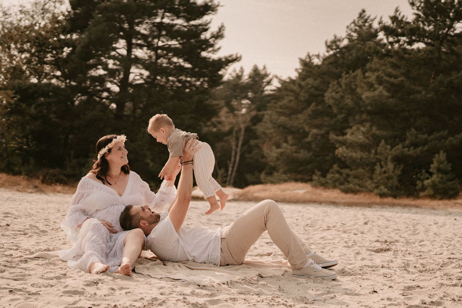 Intimate beach photoshoot with couple lounging on sand during sunset.