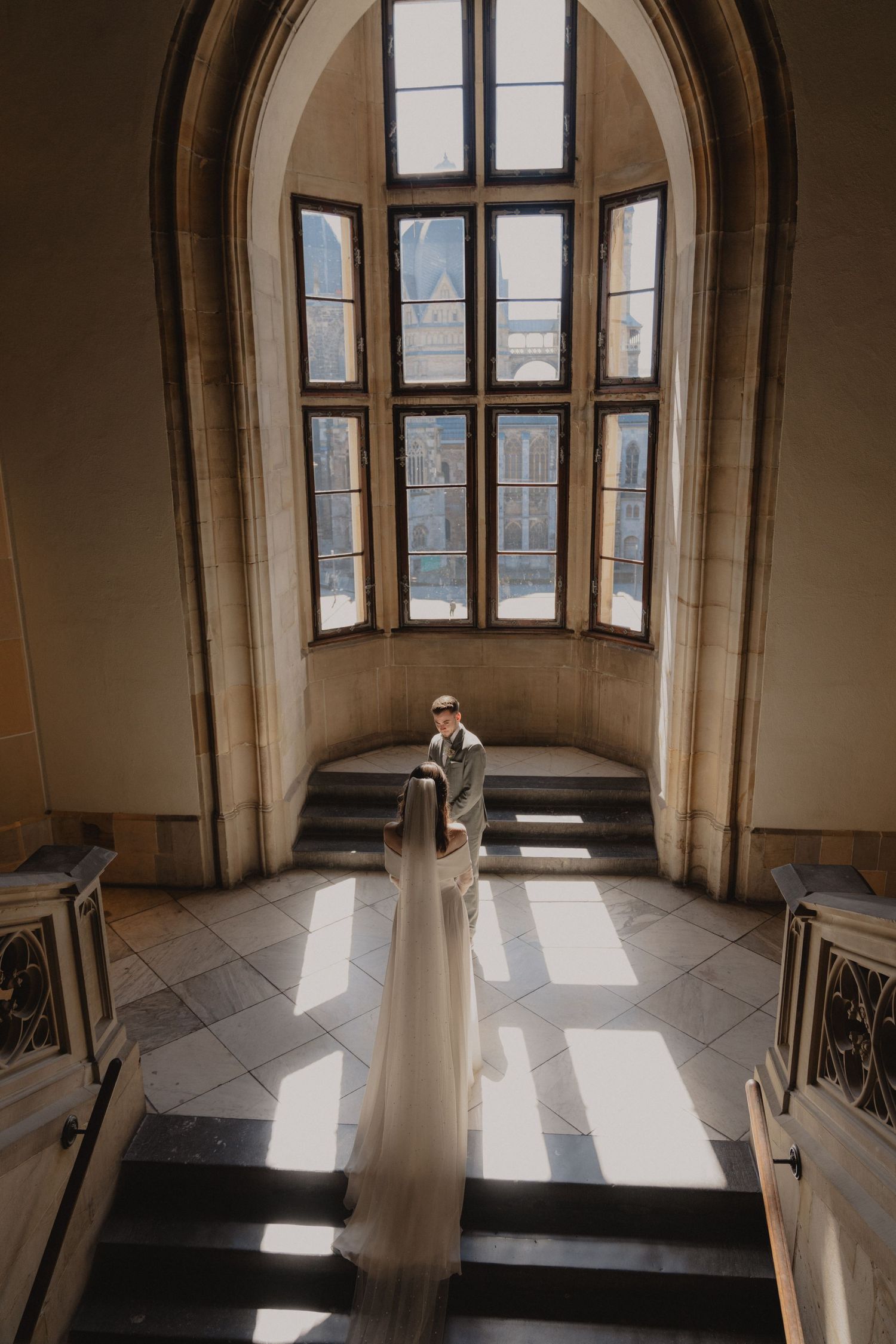Sunlit arched windows in historic building interior with dramatic shadows.