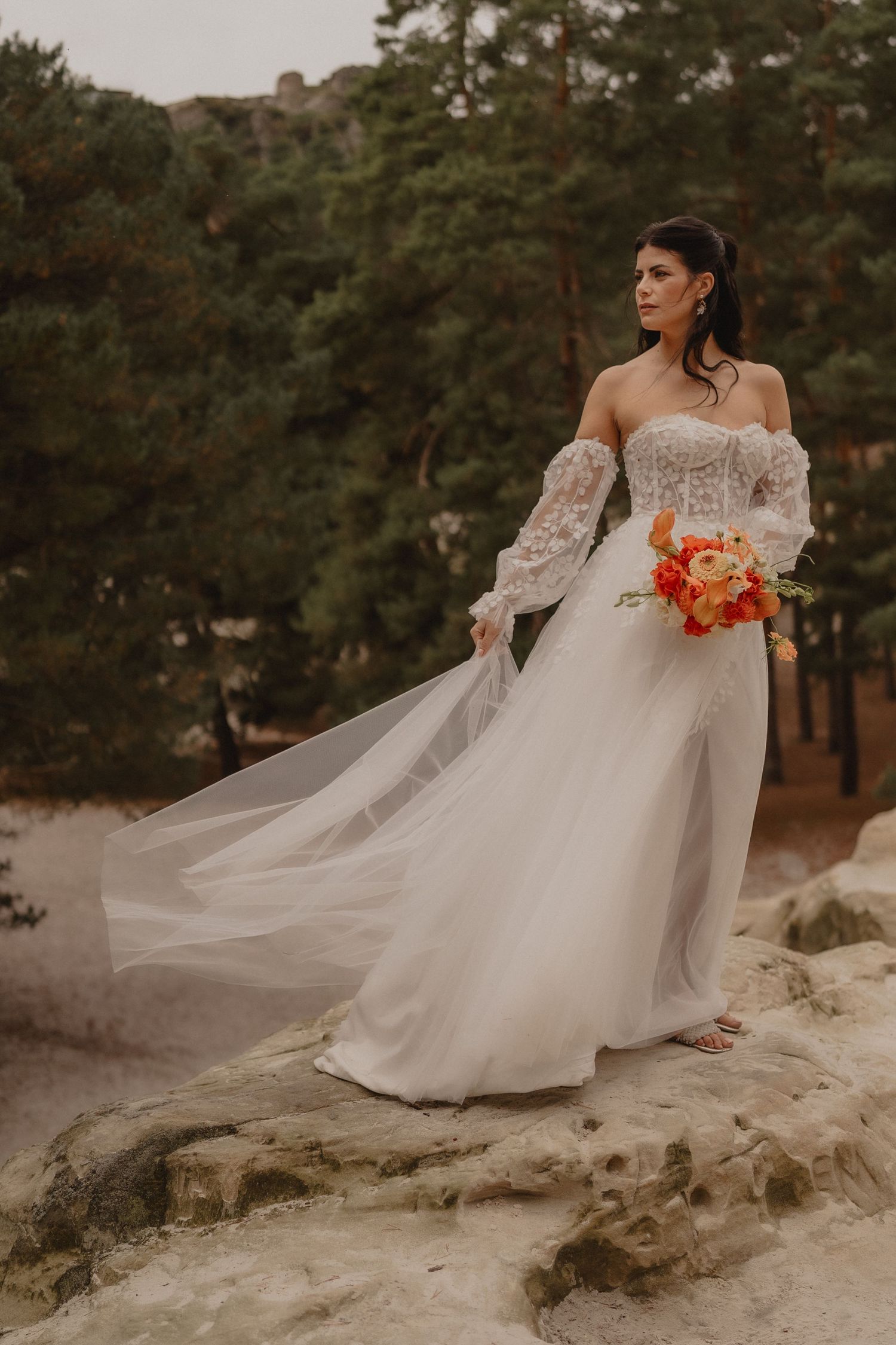 Flowing white wedding dress with lace details captured against a natural outdoor backdrop.