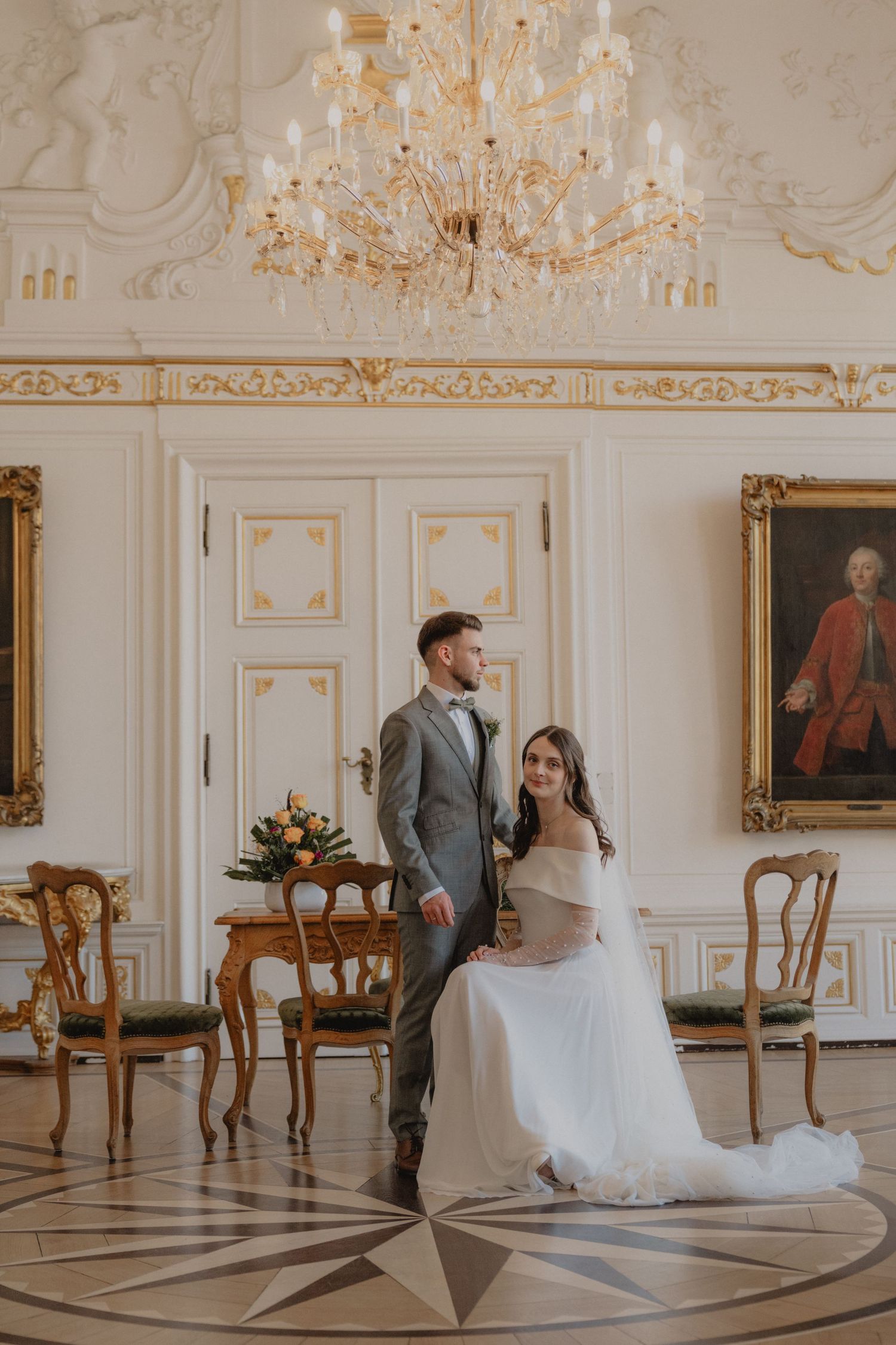 Elegant white ballroom with crystal chandelier and ornate gold details.