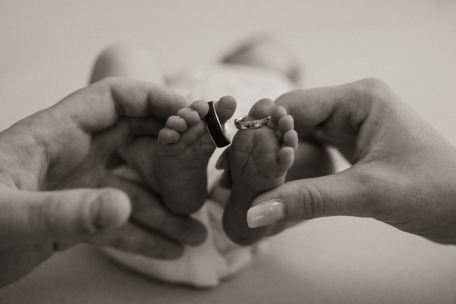 Two hands gently hold and caress each other against a soft neutral background.