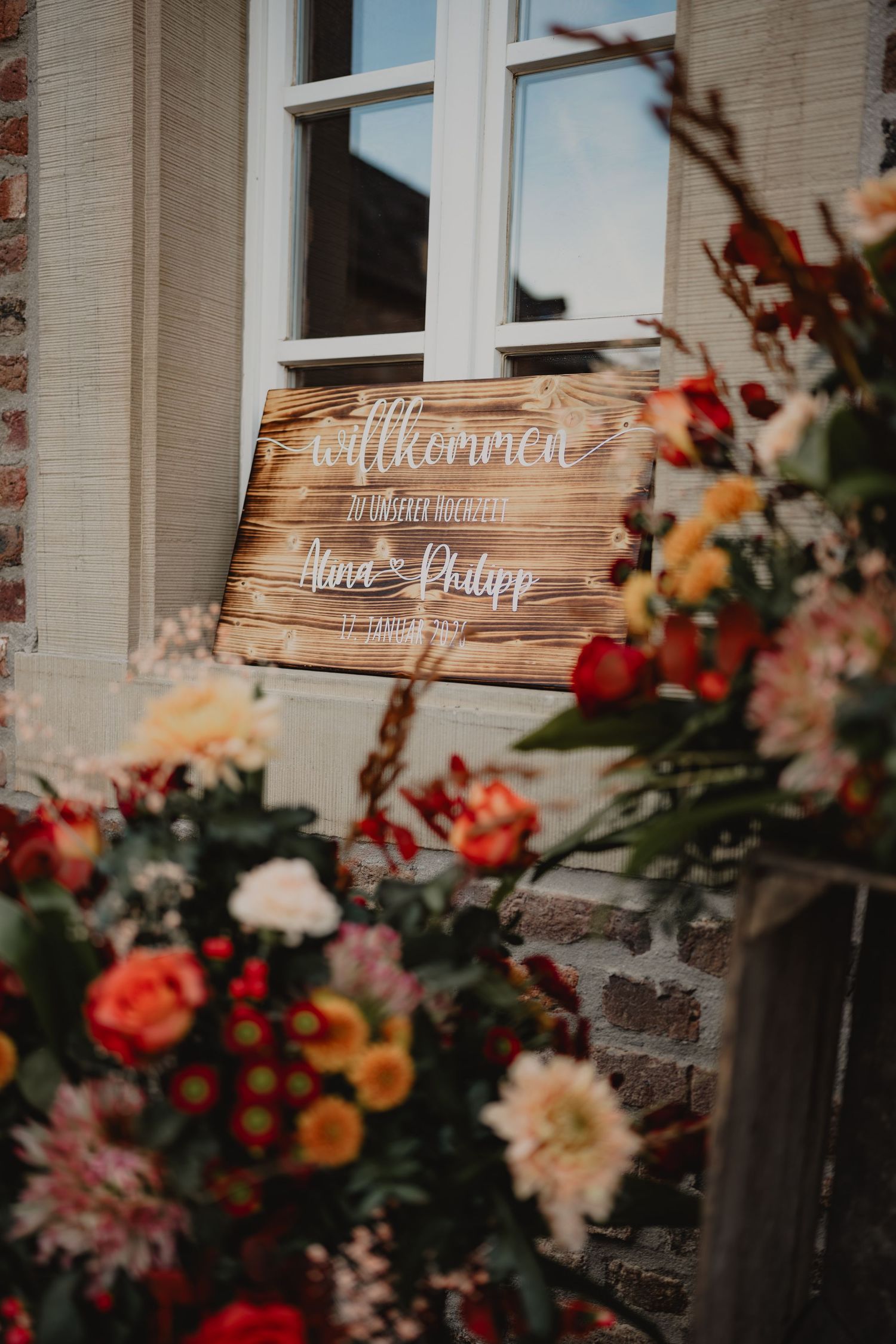 Rustic wooden welcome signs decorated with flowers at a wedding venue entrance.