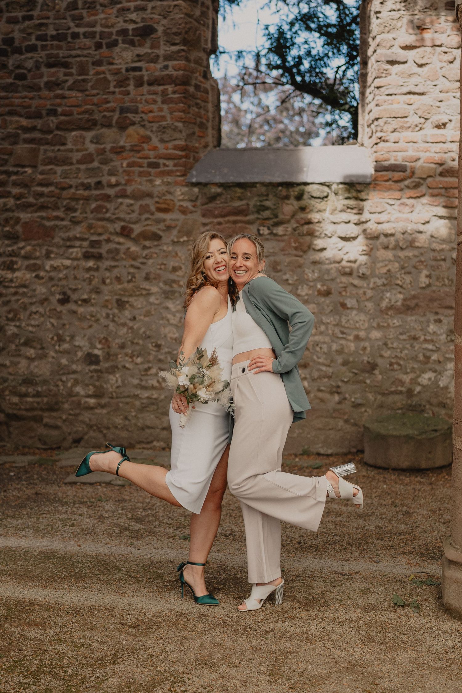 Romantic couple poses for photos against rustic stone wall backdrop.