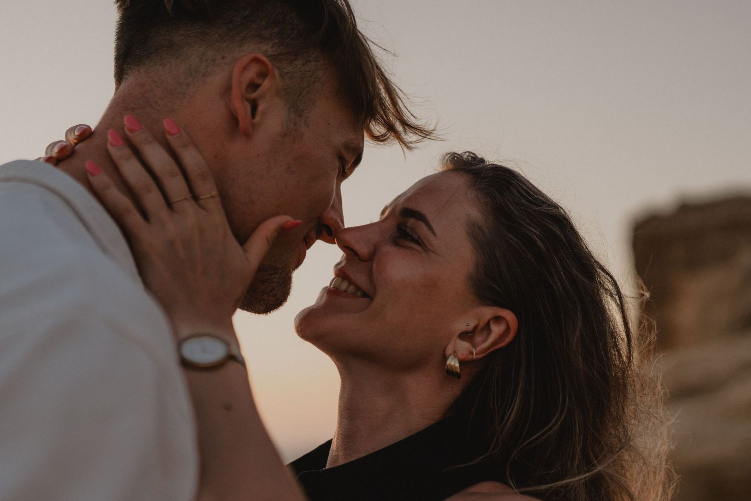 Romantic couple sharing an intimate moment, almost kissing outdoors at sunset.