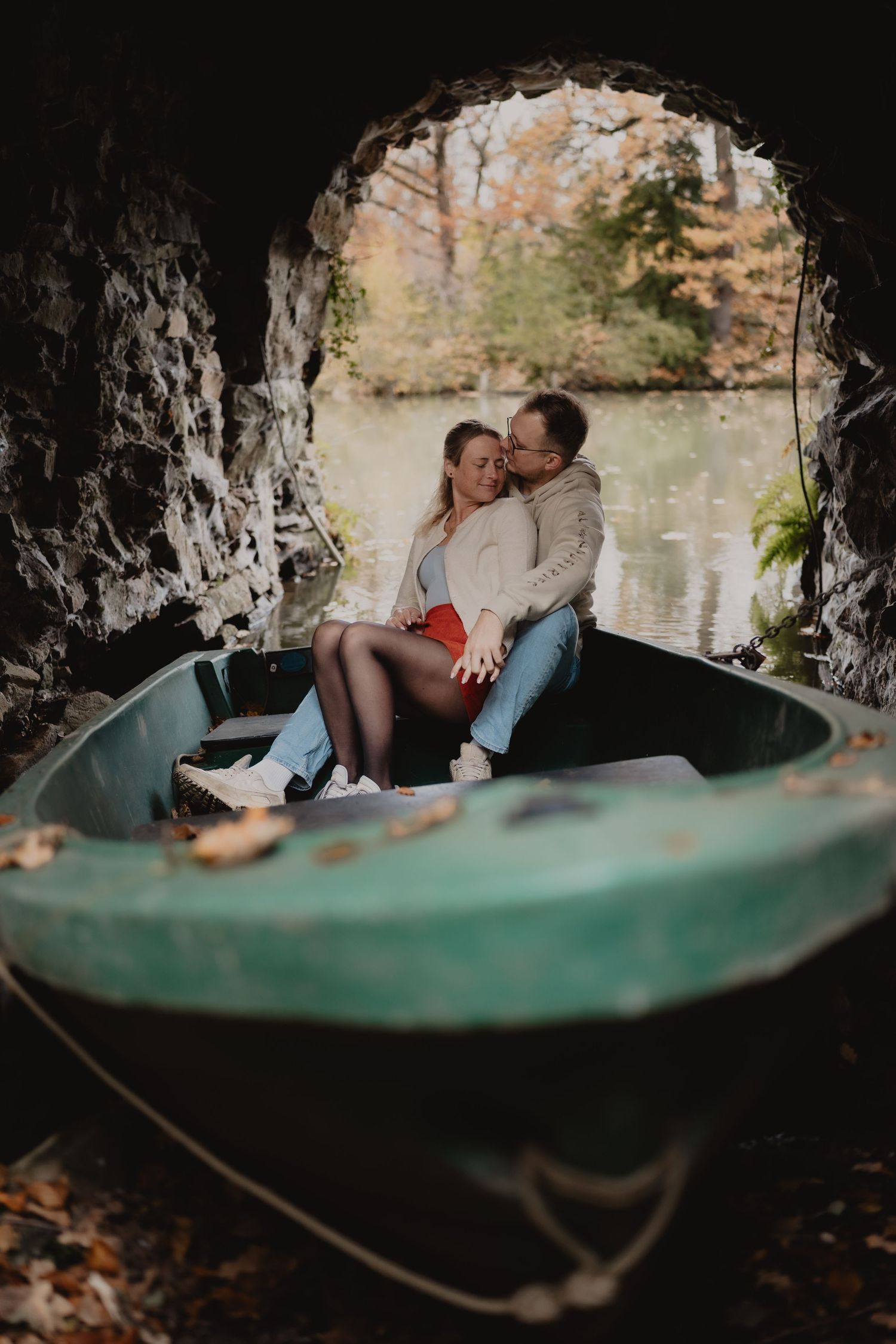 A romantic moment captured through a cave opening overlooking a serene pond.