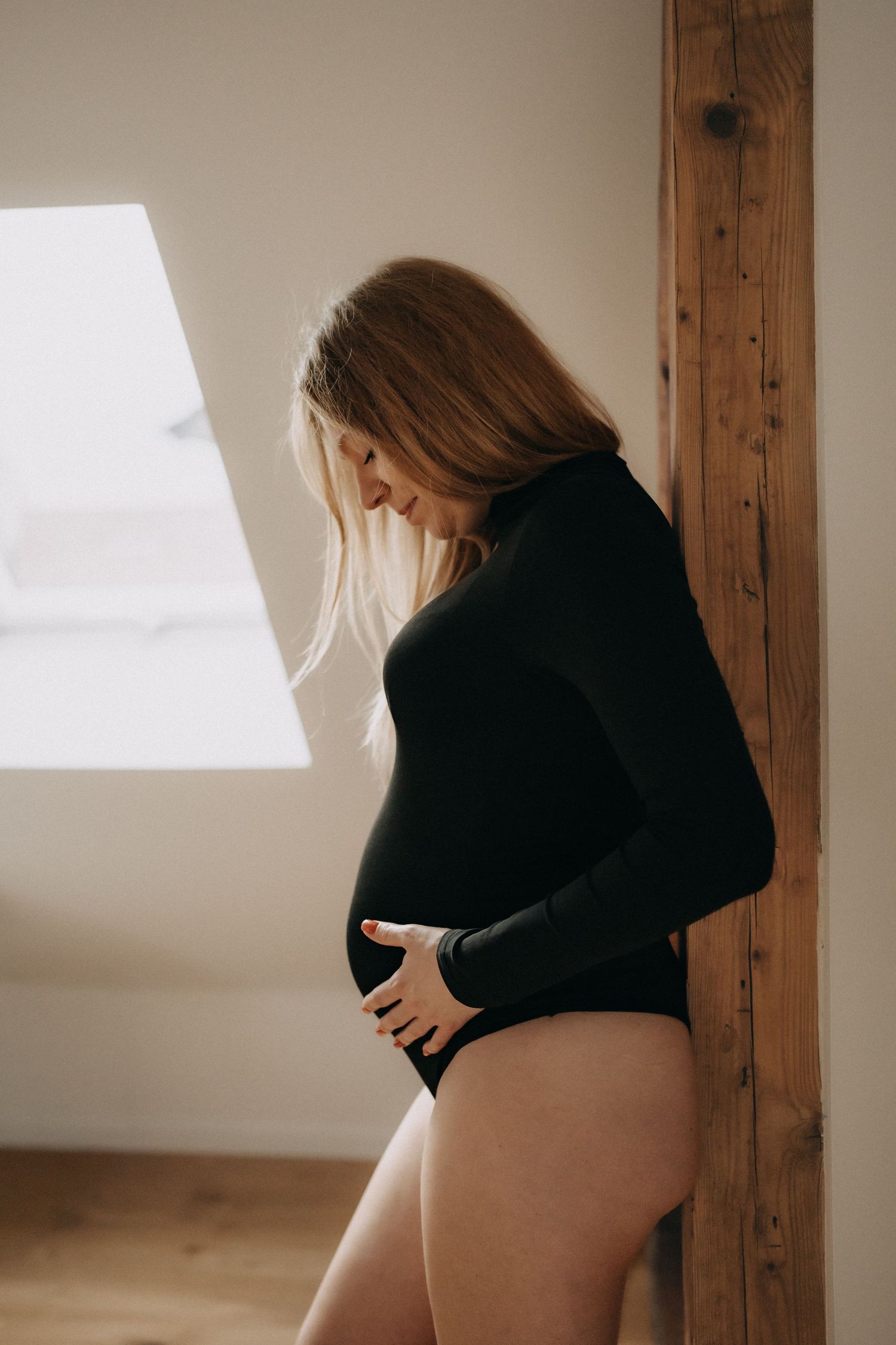 Natural light maternity photos capturing silhouette against window.