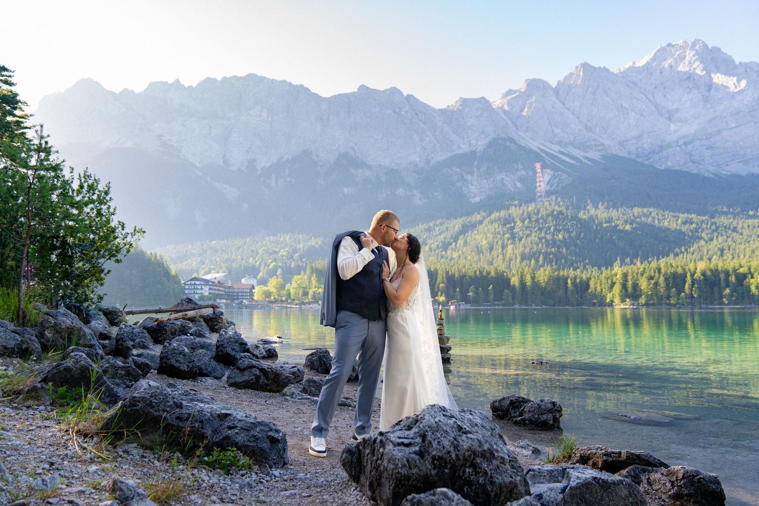 Panoramic wedding photography captures newlyweds against a backdrop of majestic mountains and a serene lake.