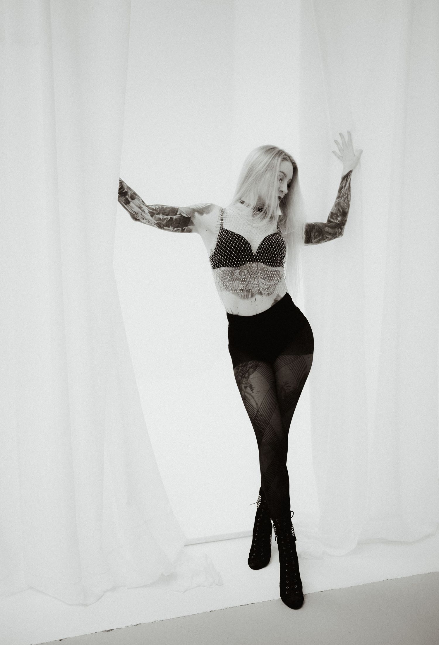 A person in black clothing poses expressively against a white backdrop in a series of artistic dance movements.