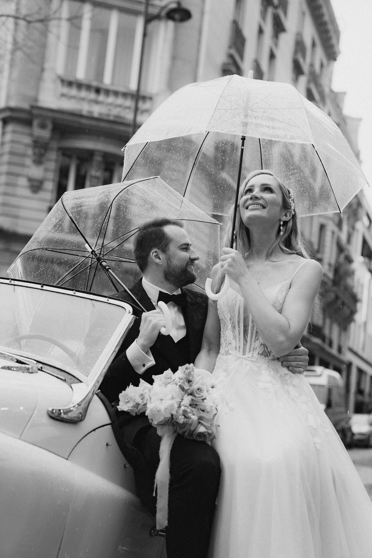 Black and white wedding photos featuring newlyweds with transparent umbrellas on a rainy Parisian street.