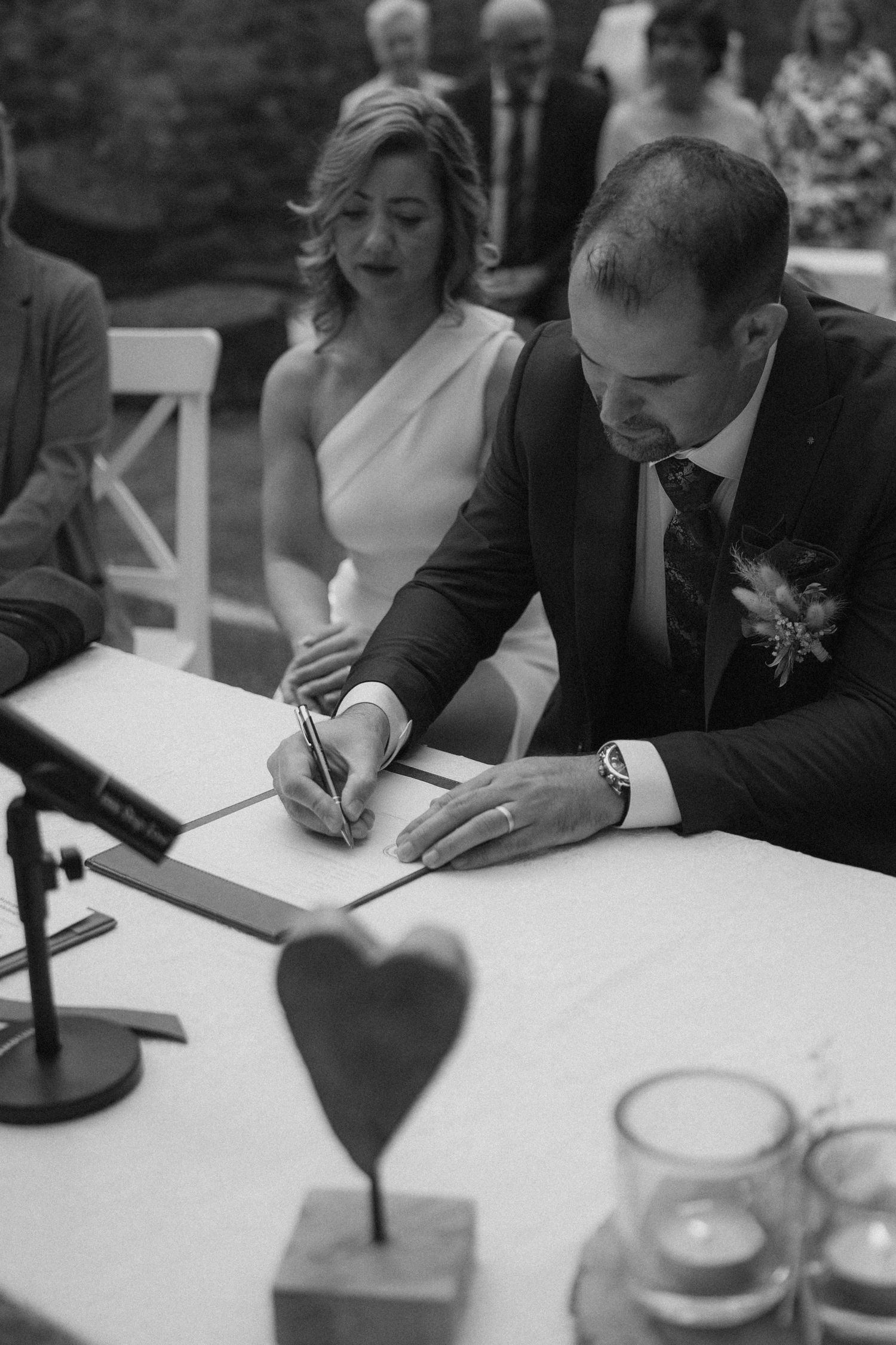 Black and white photo of guests signing the wedding registry book at an elegant ceremony.