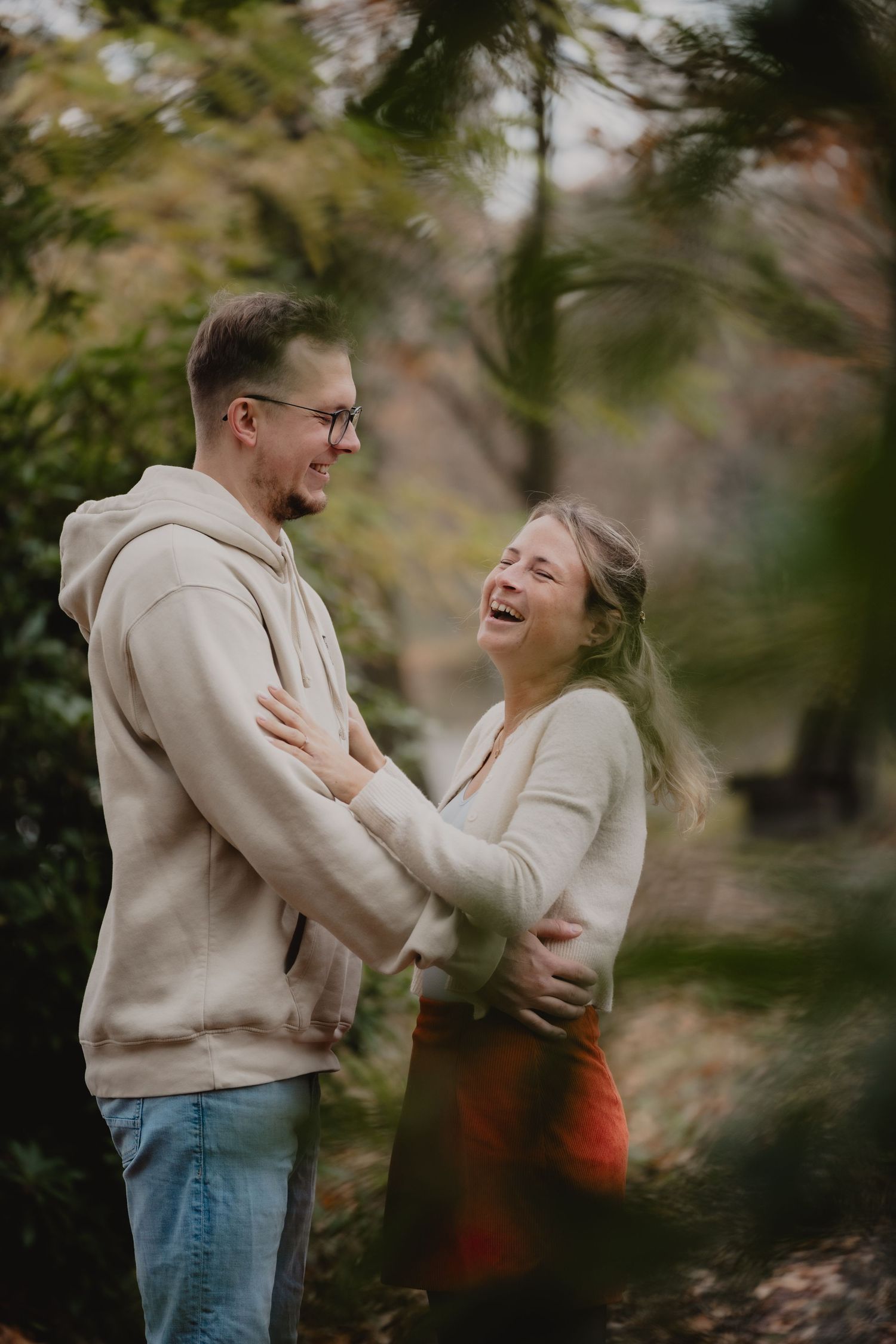 Two people share joyful laughter during an autumn outdoor photo session.