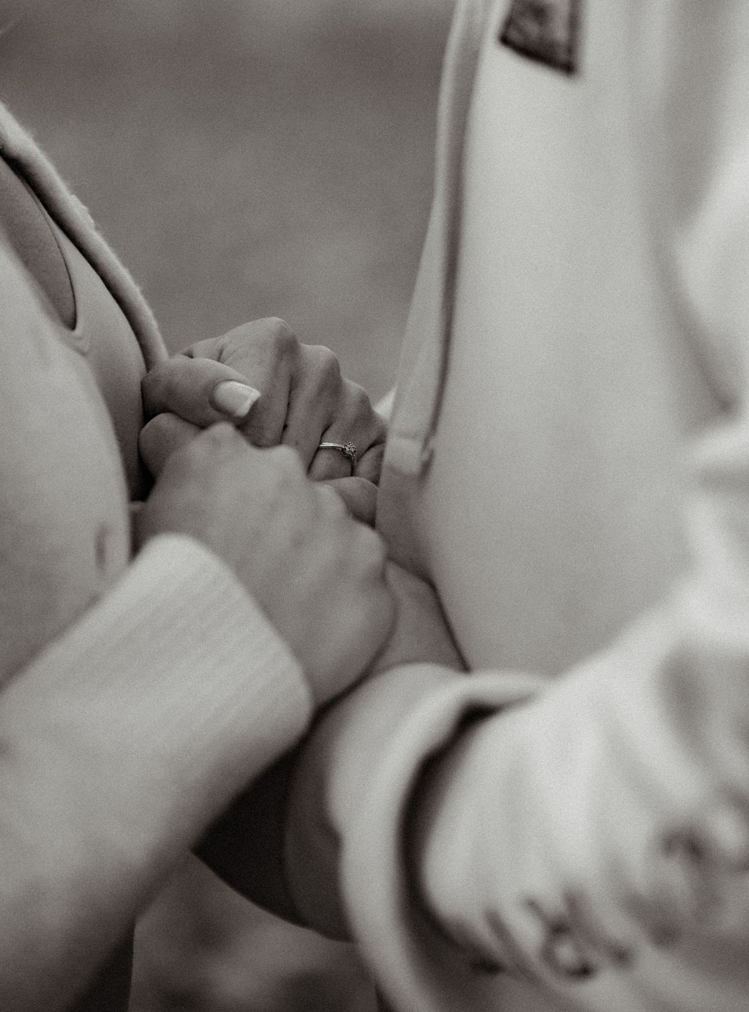 Close-up black and white photo of hands tenderly touching during an intimate moment.