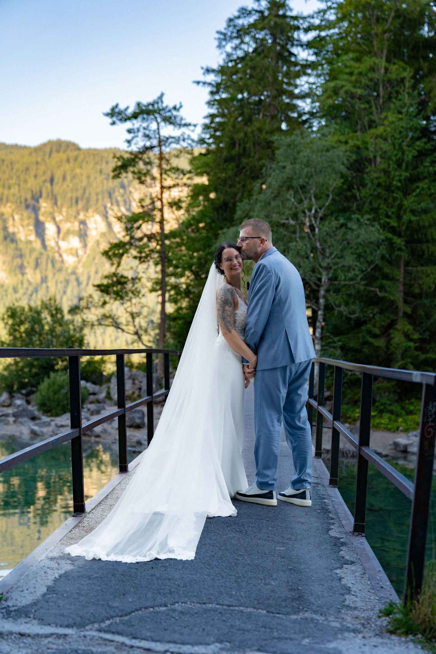 A romantic wedding photo session on a scenic mountain overlook with evergreen trees and mountain views.